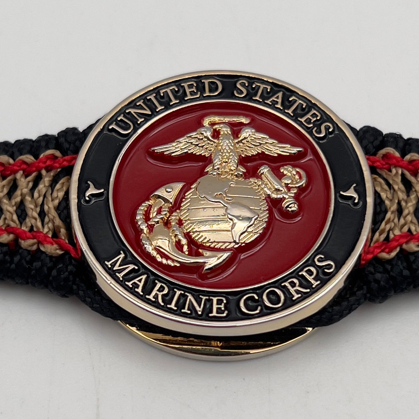 Thin, narrow, flexible and comfortable braided United States Marine Corps bracelet featuring a 24K gold plated USMC Eagle Globe and Anchor medallion, a black Cobra style tactical buckle and woven with black Type-1 paracord and Imperial Red and Gold nano cord.