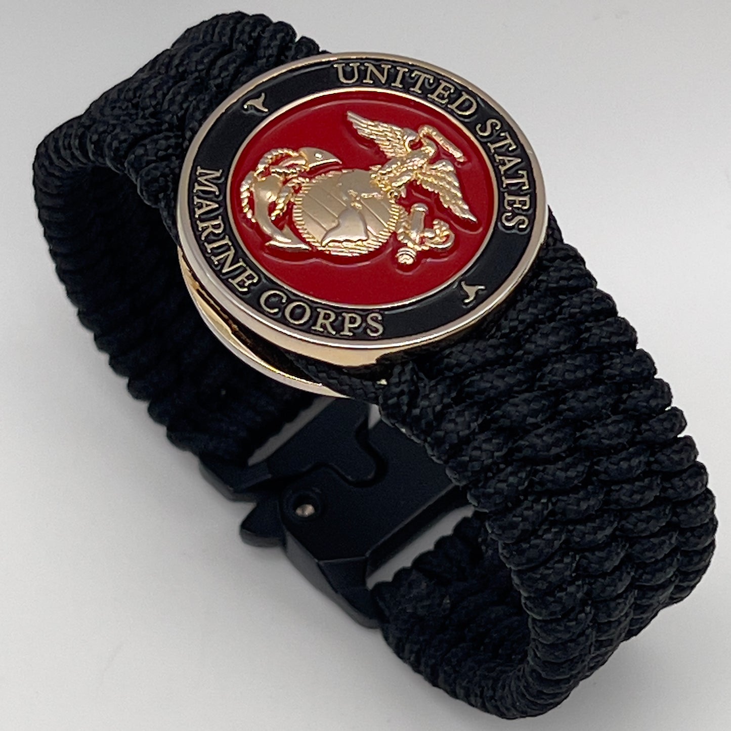 Thin, medium width, flexible and comfortable braided United States Marine Corps bracelet featuring a 24K gold plated USMC officer Eagle Globe and Anchor medallion, a black Cobra style tactical buckle and woven with black Type-1 paracord.
