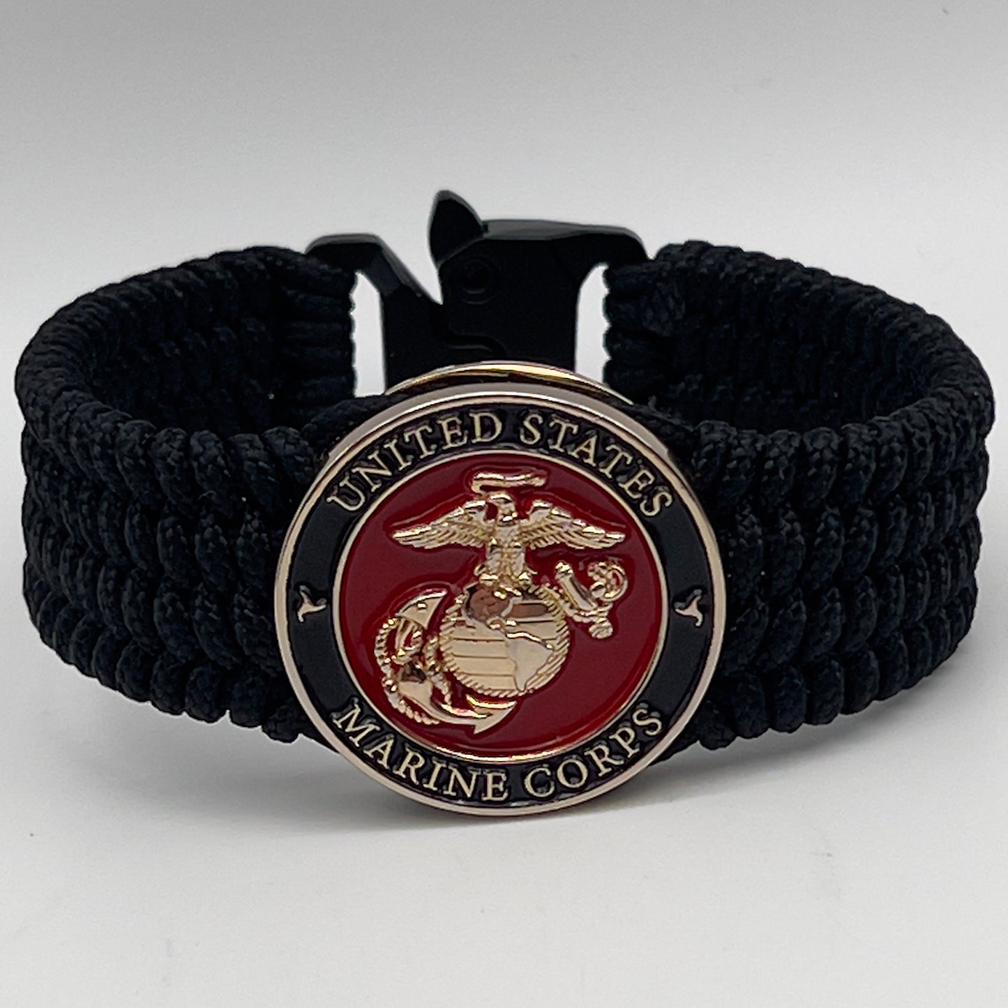 Thin, medium width, flexible and comfortable braided United States Marine Corps bracelet featuring a 24K gold plated USMC officer Eagle Globe and Anchor medallion, a black Cobra style tactical buckle and woven with black Type-1 paracord.