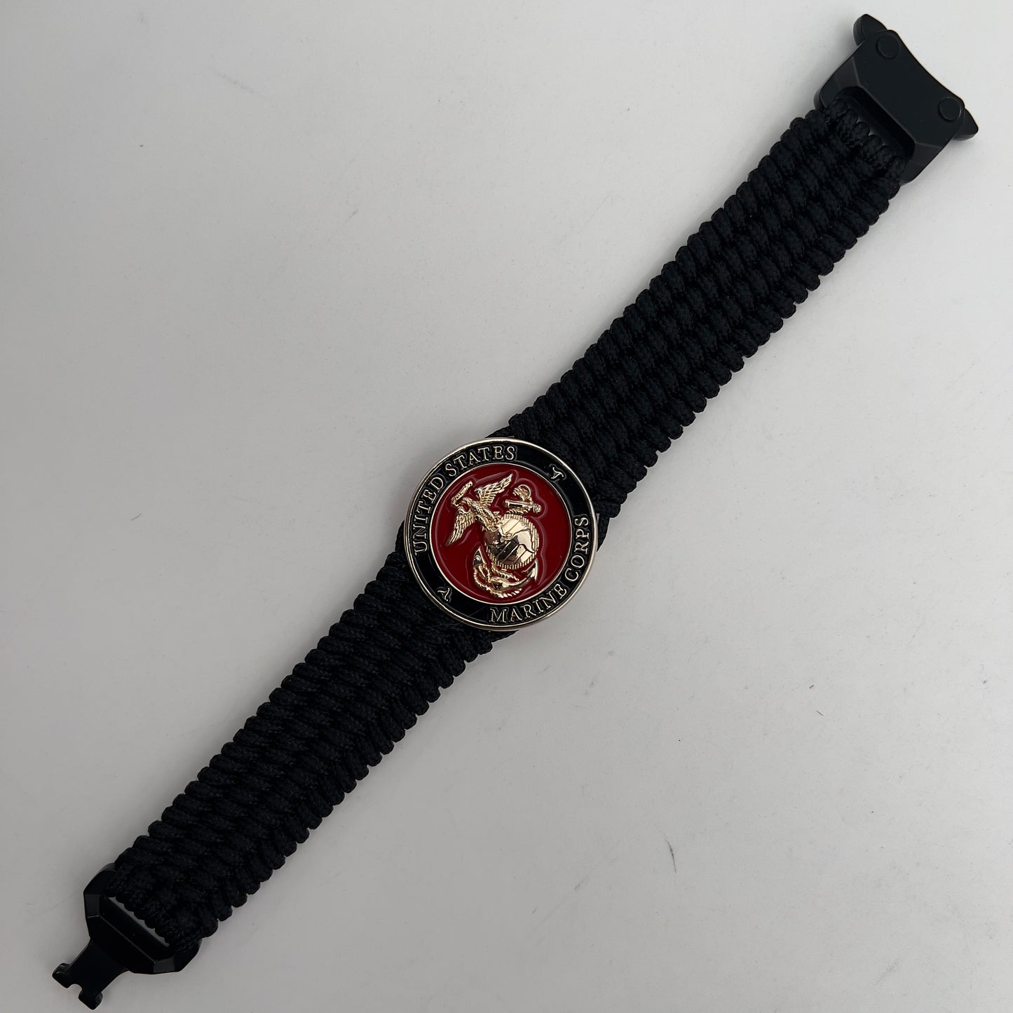 Thin, medium width, flexible and comfortable braided United States Marine Corps bracelet featuring a 24K gold plated USMC officer Eagle Globe and Anchor medallion, a black Cobra style tactical buckle and woven with black Type-1 paracord.