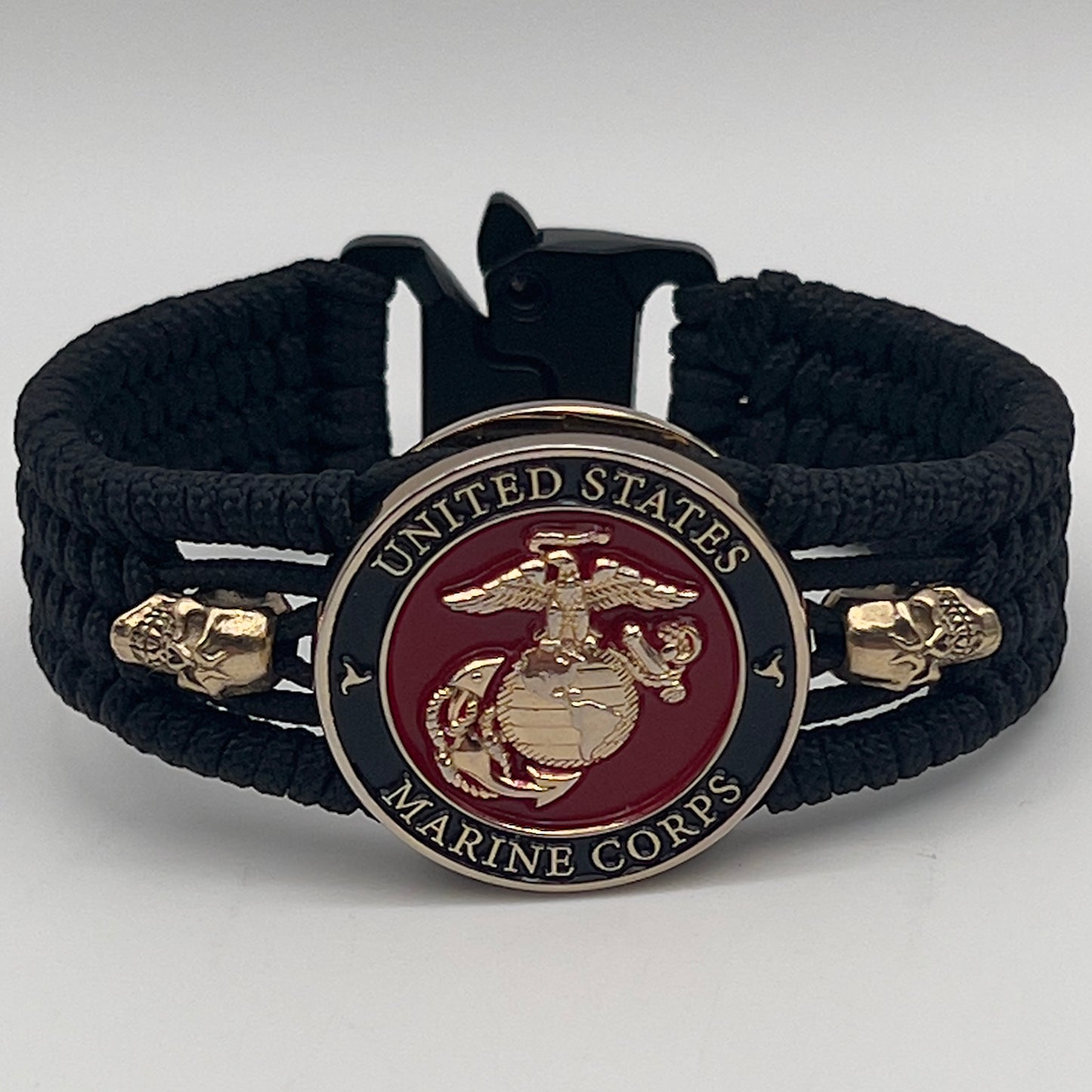 Thin, medium width, flexible and comfortable braided United States Marine Corps bracelet featuring a 24K gold plated USMC officer Eagle Globe and Anchor medallion, two gold plated skulls, a black Cobra style tactical buckle and woven with black Type-1 paracord.
