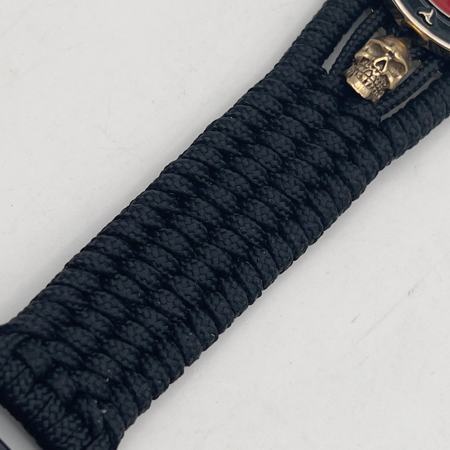Thin, medium width, flexible and comfortable braided United States Marine Corps bracelet featuring a 24K gold plated USMC officer Eagle Globe and Anchor medallion, two gold plated skulls, a black Cobra style tactical buckle and woven with black Type-1 paracord.