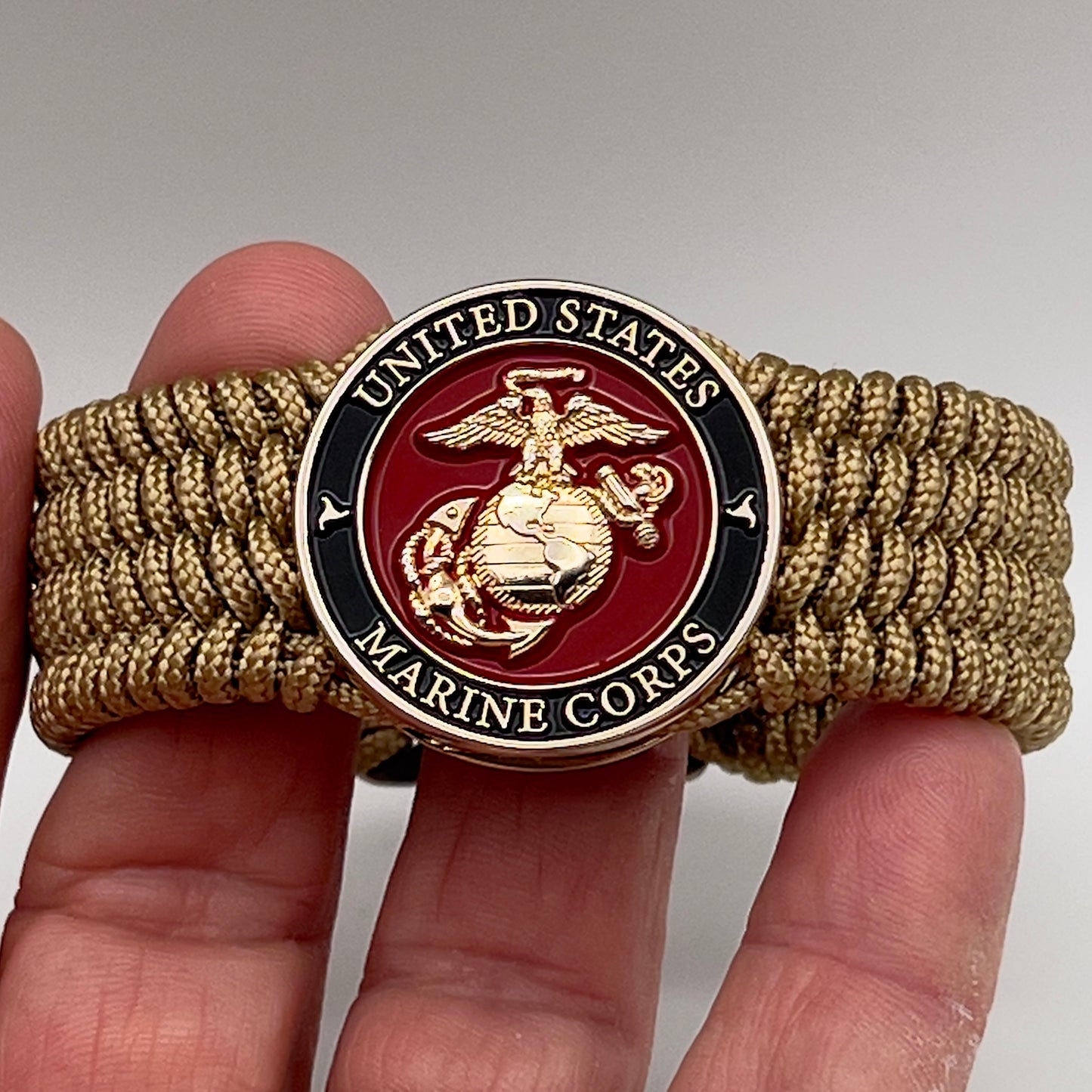 Thin, medium width, flexible and comfortable braided United States Marine Corps bracelet featuring a 24K gold plated USMC officer Eagle Globe and Anchor medallion, a gold Cobra style tactical buckle and woven with gold Type-1 paracord.