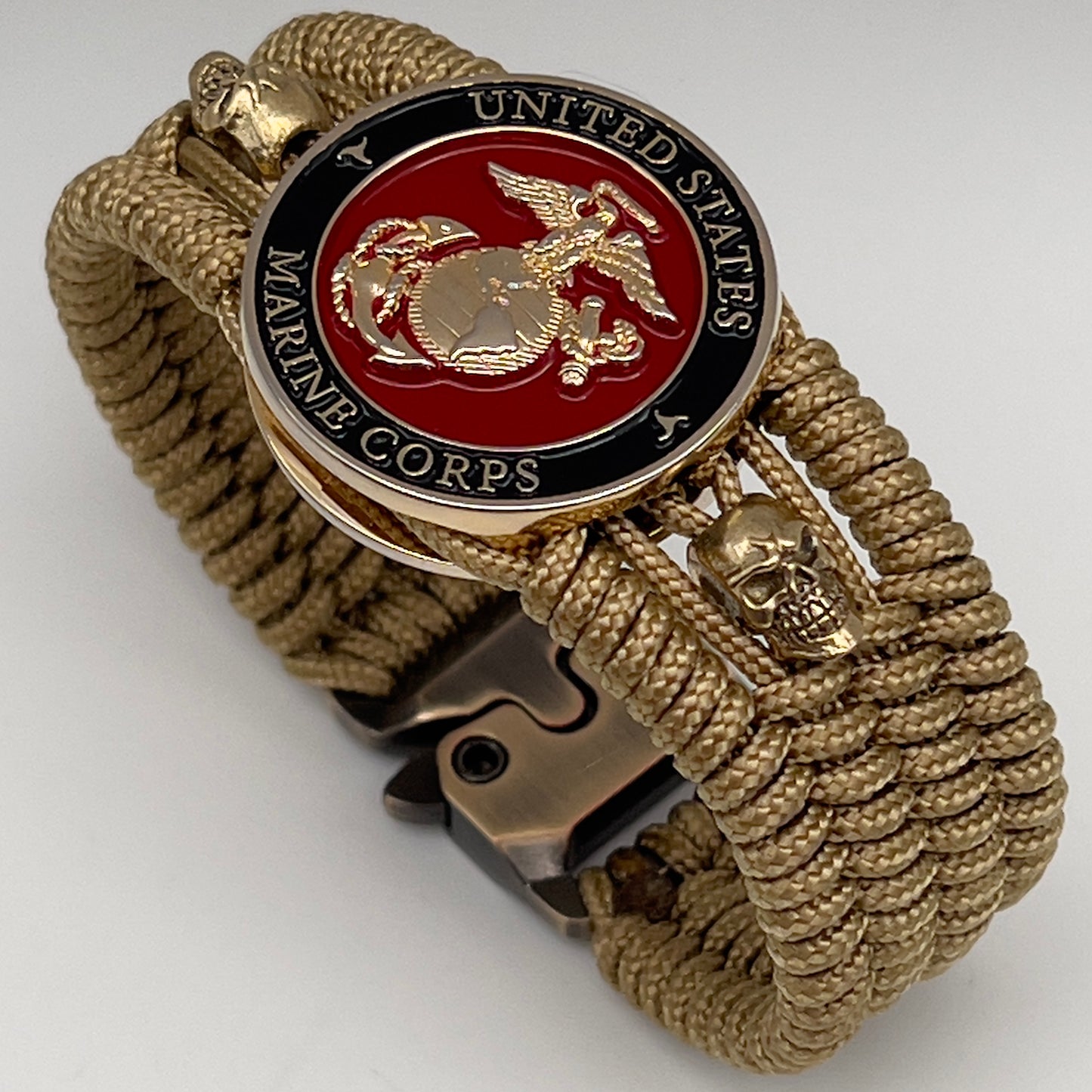 Thin, medium width, flexible and comfortable braided United States Marine Corps bracelet featuring a 24K gold plated USMC officer Eagle Globe and Anchor medallion, two gold plated skulls, a gold Cobra style tactical buckle and woven with gold Type-1 paracord.