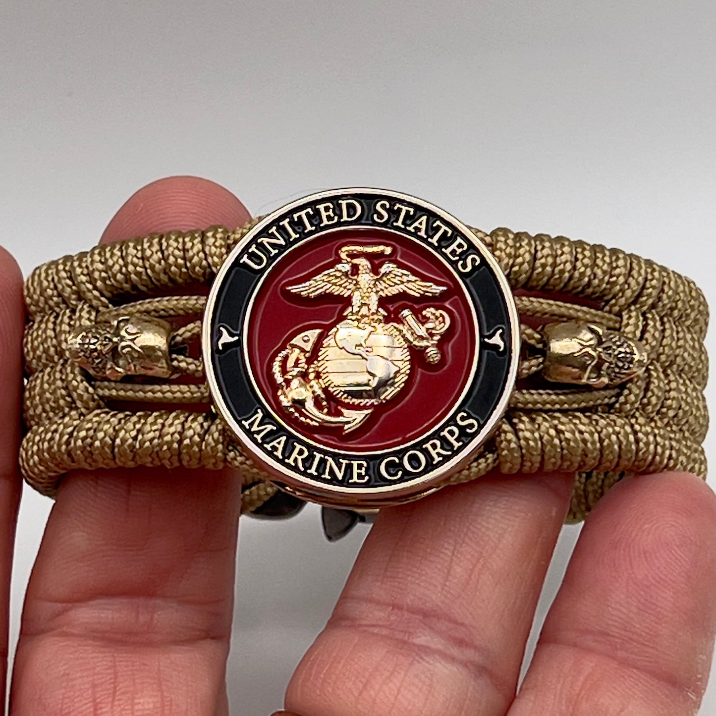 Thin, medium width, flexible and comfortable braided United States Marine Corps bracelet featuring a 24K gold plated USMC officer Eagle Globe and Anchor medallion, two gold plated skulls, a gold Cobra style tactical buckle and woven with gold Type-1 paracord.