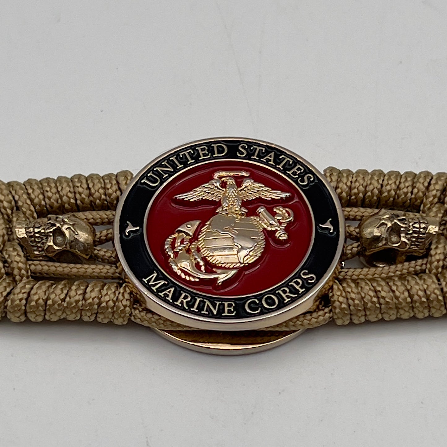 Thin, medium width, flexible and comfortable braided United States Marine Corps bracelet featuring a 24K gold plated USMC officer Eagle Globe and Anchor medallion, two gold plated skulls, a gold Cobra style tactical buckle and woven with gold Type-1 paracord.