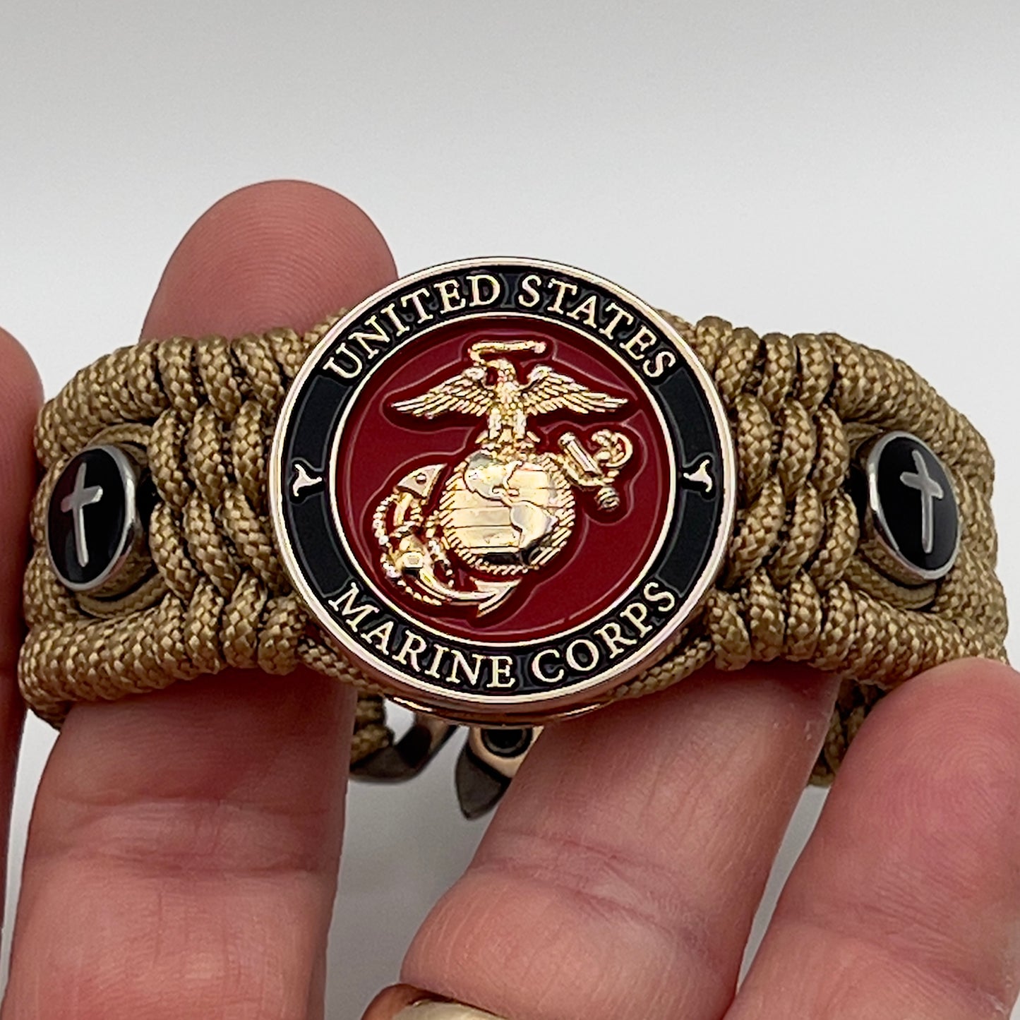 Thin, medium width, flexible and comfortable braided United States Marine Corps bracelet featuring a 24K gold plated USMC officer Eagle Globe and Anchor medallion, two Christian crosses, a gold Cobra style tactical buckle and woven with gold Type-1 paracord.
