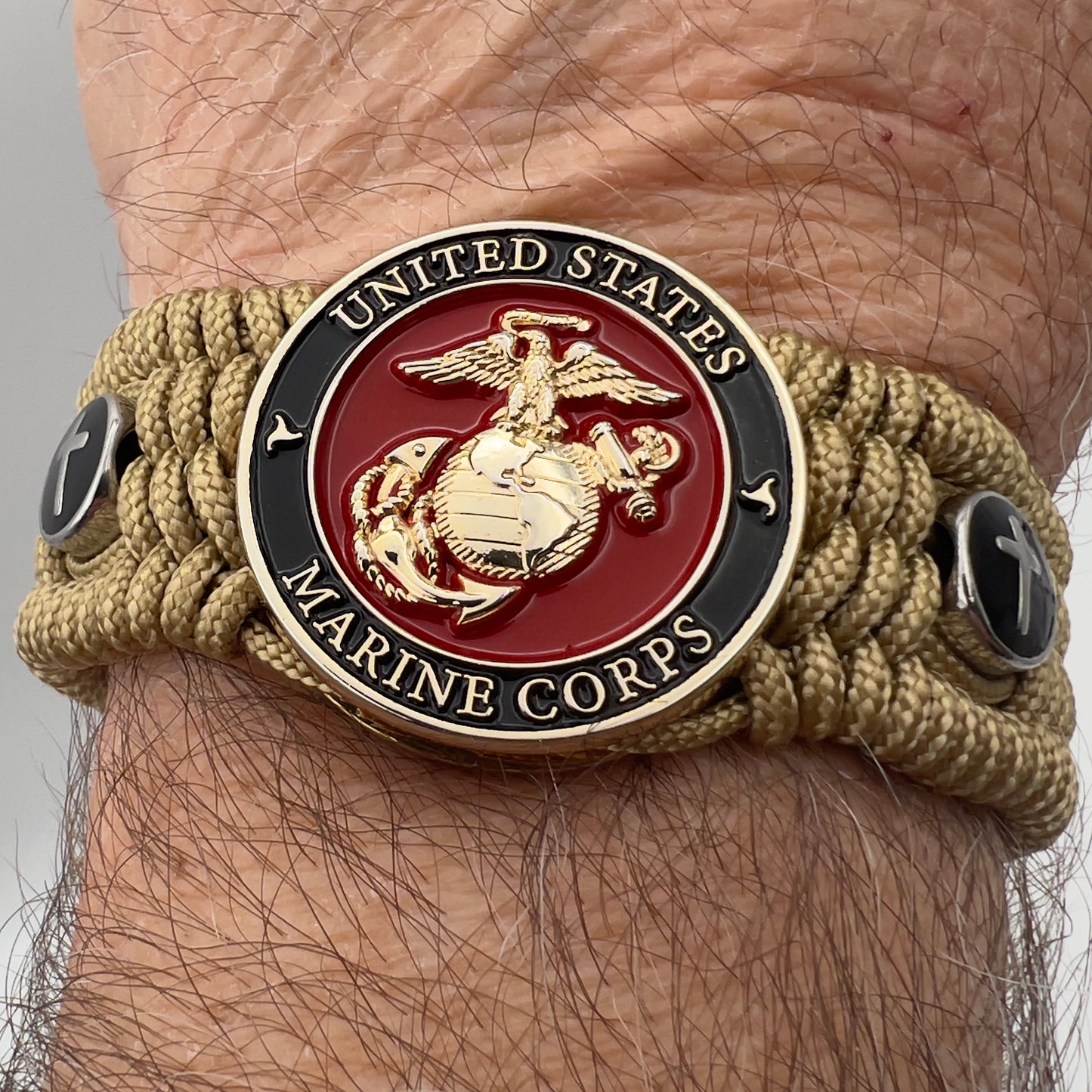 Thin, medium width, flexible and comfortable braided United States Marine Corps bracelet featuring a 24K gold plated USMC officer Eagle Globe and Anchor medallion, two Christian crosses, a gold Cobra style tactical buckle and woven with gold Type-1 paracord.