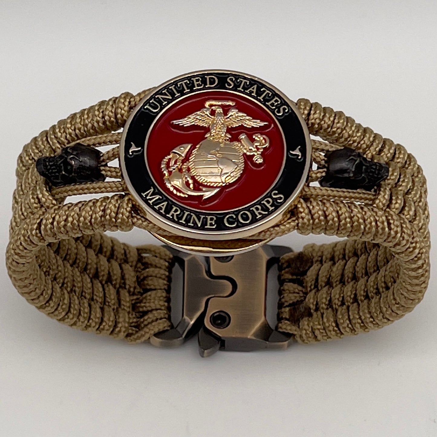 Thin, medium width, flexible and comfortable braided United States Marine Corps bracelet featuring a 24K gold plated USMC officer Eagle Globe and Anchor medallion, two black micro skulls, a gold Cobra style tactical buckle and woven with gold Type-1 paracord.