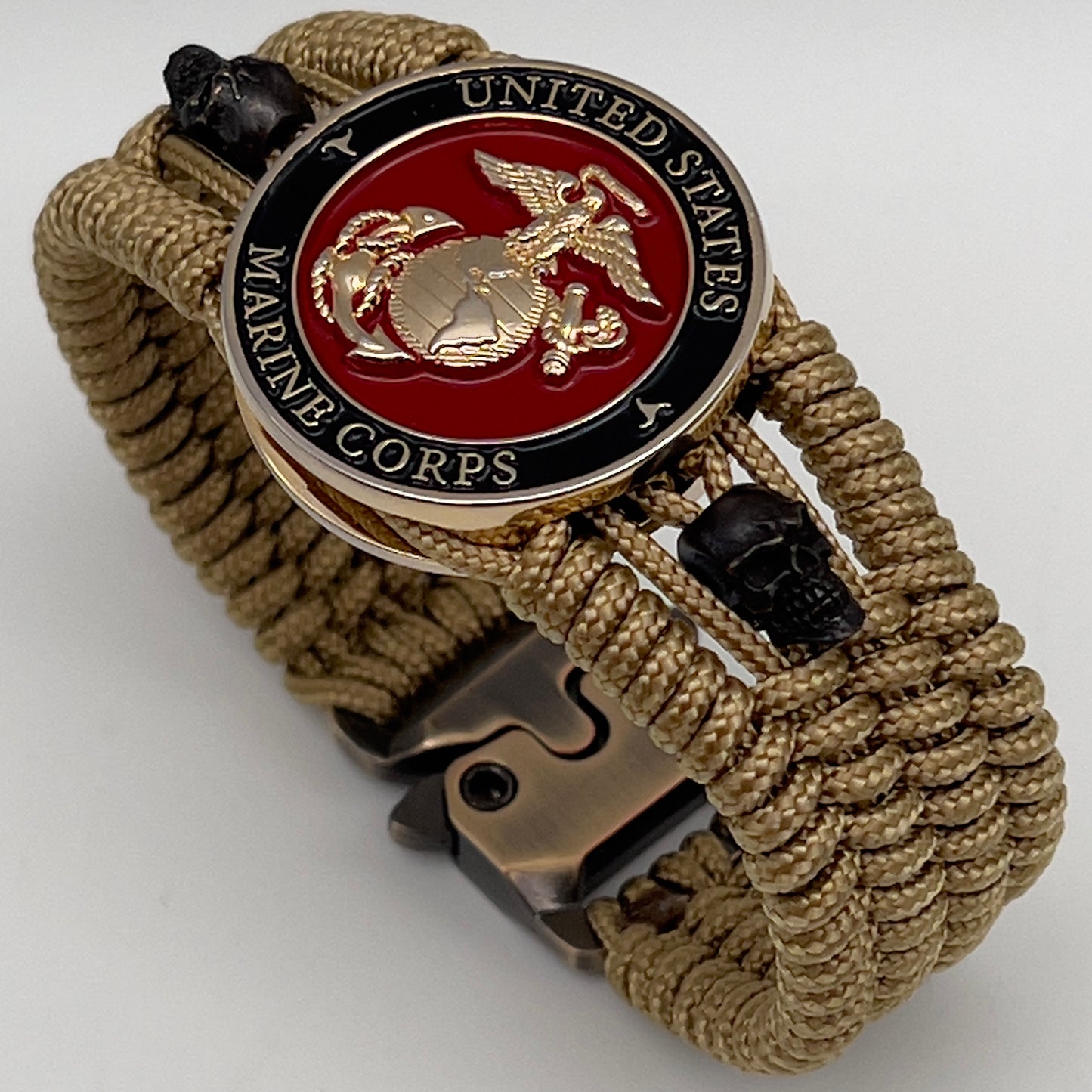 Thin, medium width, flexible and comfortable braided United States Marine Corps bracelet featuring a 24K gold plated USMC officer Eagle Globe and Anchor medallion, two black micro skulls, a gold Cobra style tactical buckle and woven with gold Type-1 paracord.