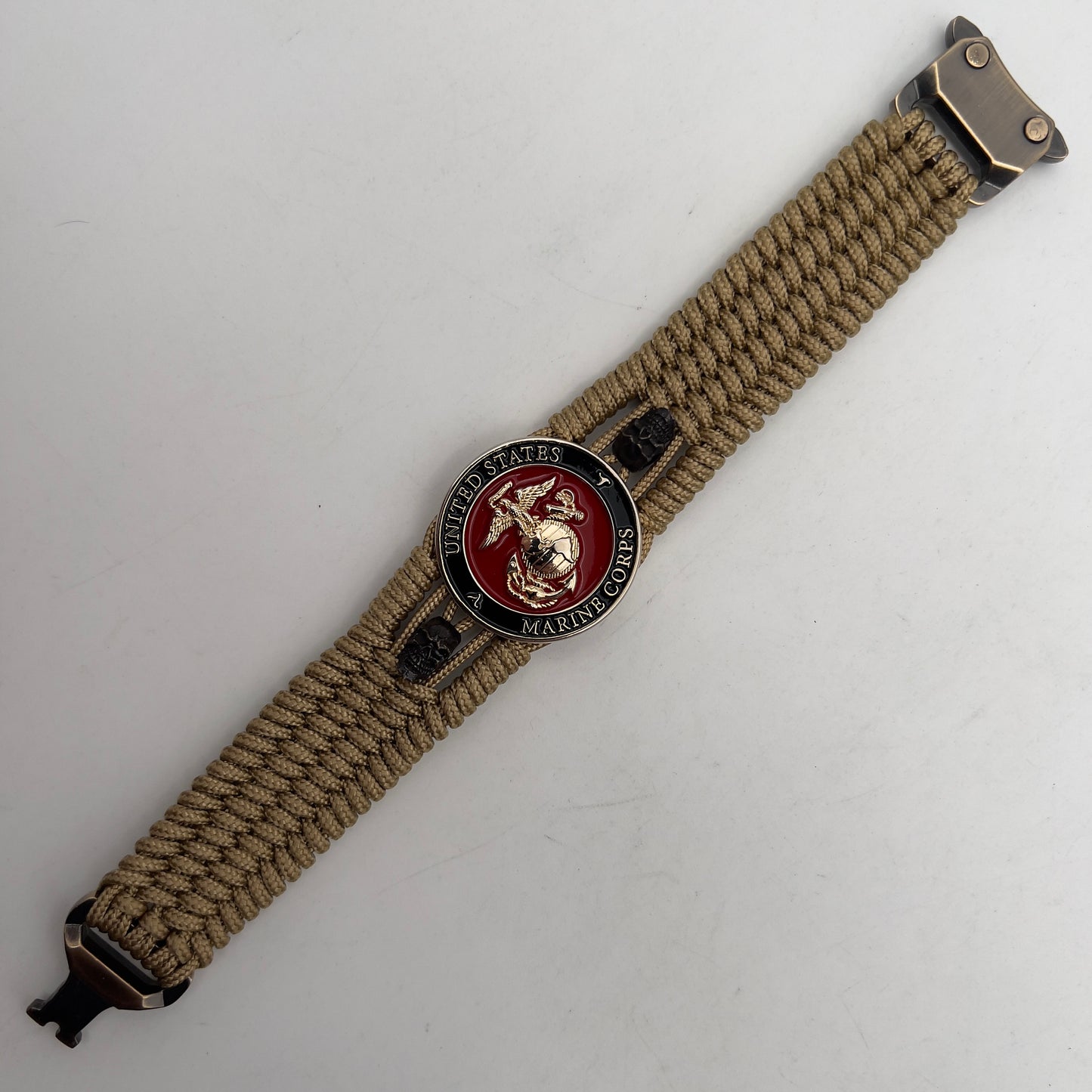Thin, medium width, flexible and comfortable braided United States Marine Corps bracelet featuring a 24K gold plated USMC officer Eagle Globe and Anchor medallion, two black micro skulls, a gold Cobra style tactical buckle and woven with gold Type-1 paracord.