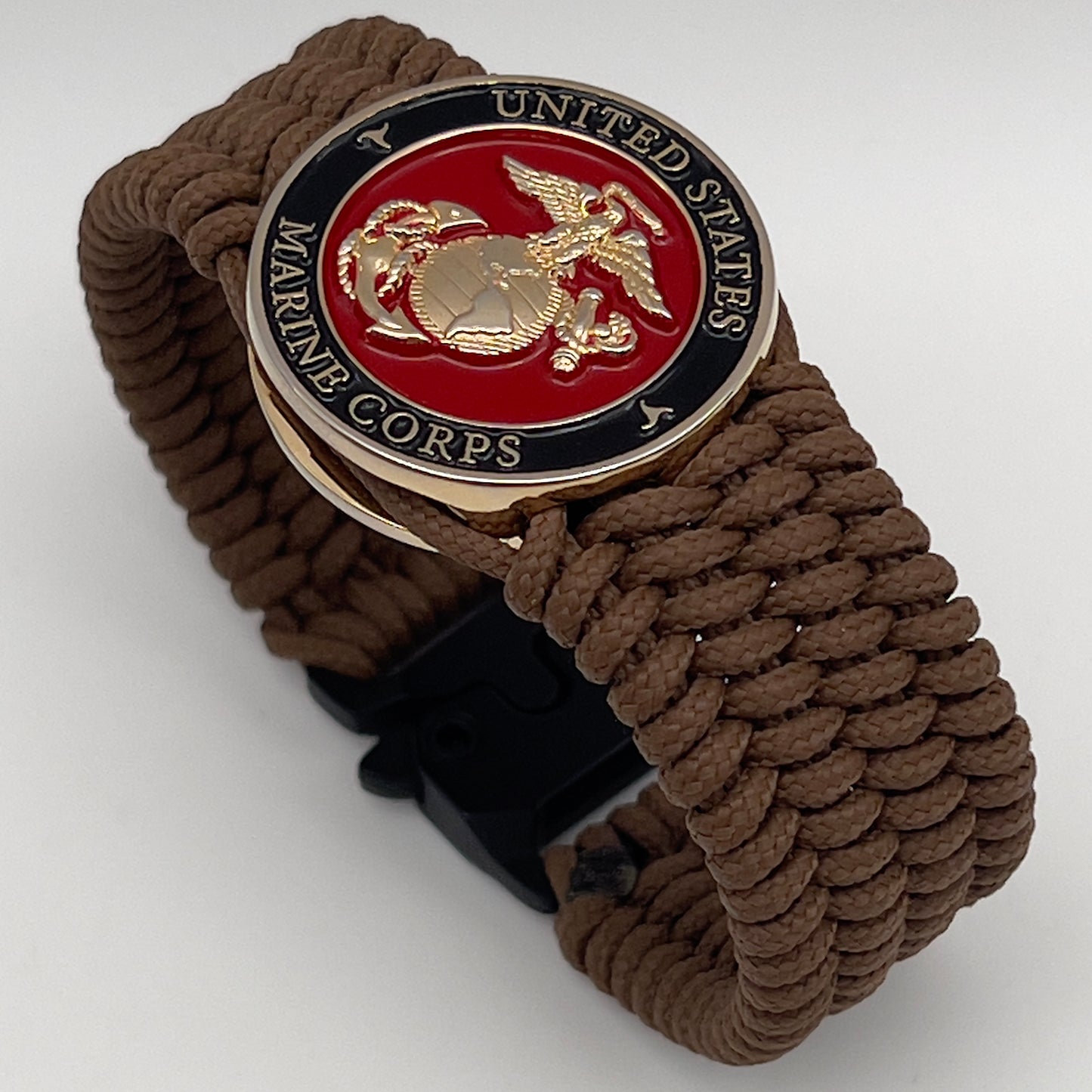 Thin, medium width, flexible and comfortable braided United States Marine Corps bracelet featuring a 24K gold plated USMC officer Eagle Globe and Anchor medallion, a gold Cobra style tactical buckle and woven with Coyote Brown Type-1 paracord.