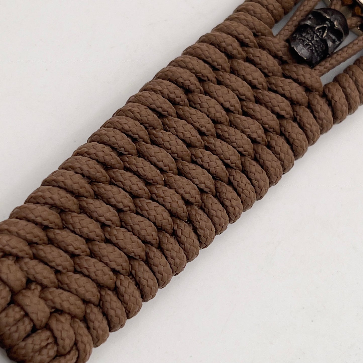 Thin, medium width, flexible and comfortable braided United States Marine Corps bracelet featuring a 24K gold plated USMC officer Eagle Globe and Anchor medallion, two black micro skulls, a black Cobra style tactical buckle and woven with Coyote Brown Type-1 paracord.