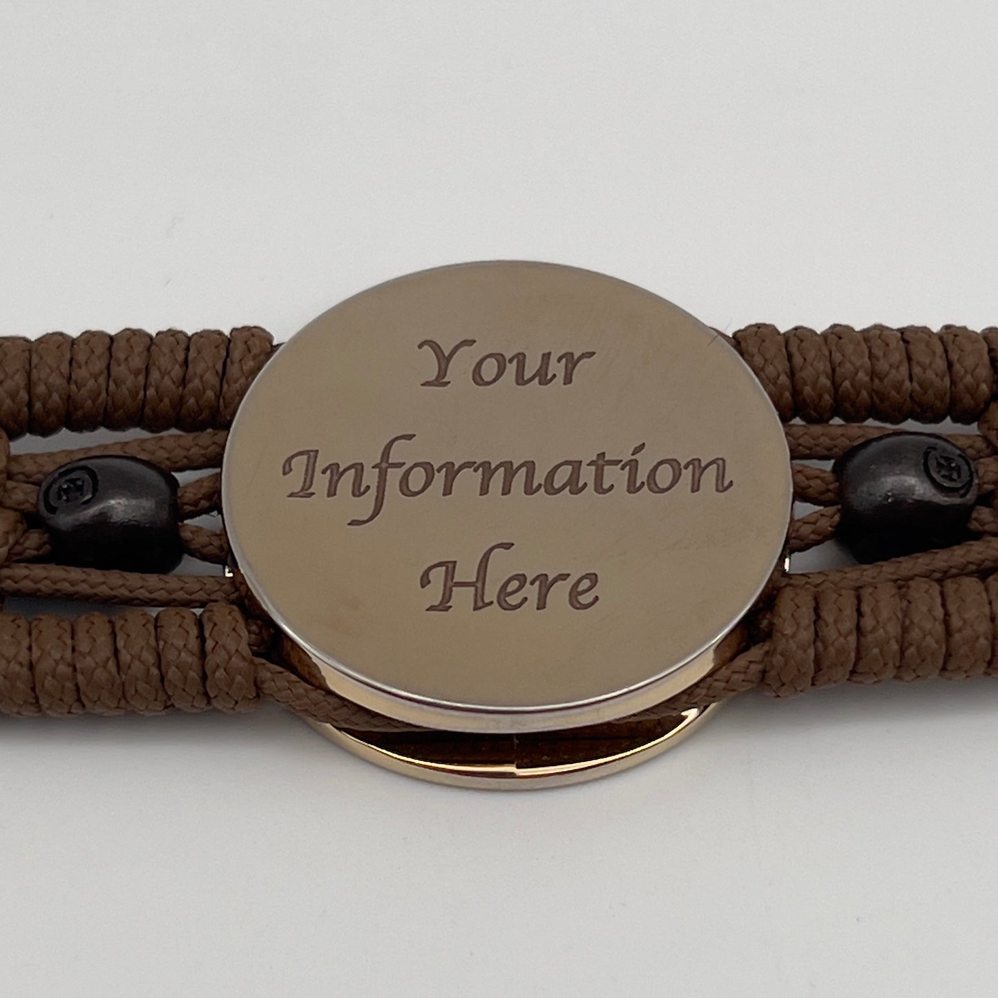Thin, medium width, flexible and comfortable braided United States Marine Corps bracelet featuring a 24K gold plated USMC officer Eagle Globe and Anchor medallion, two black micro skulls, a black Cobra style tactical buckle and woven with Coyote Brown Type-1 paracord.