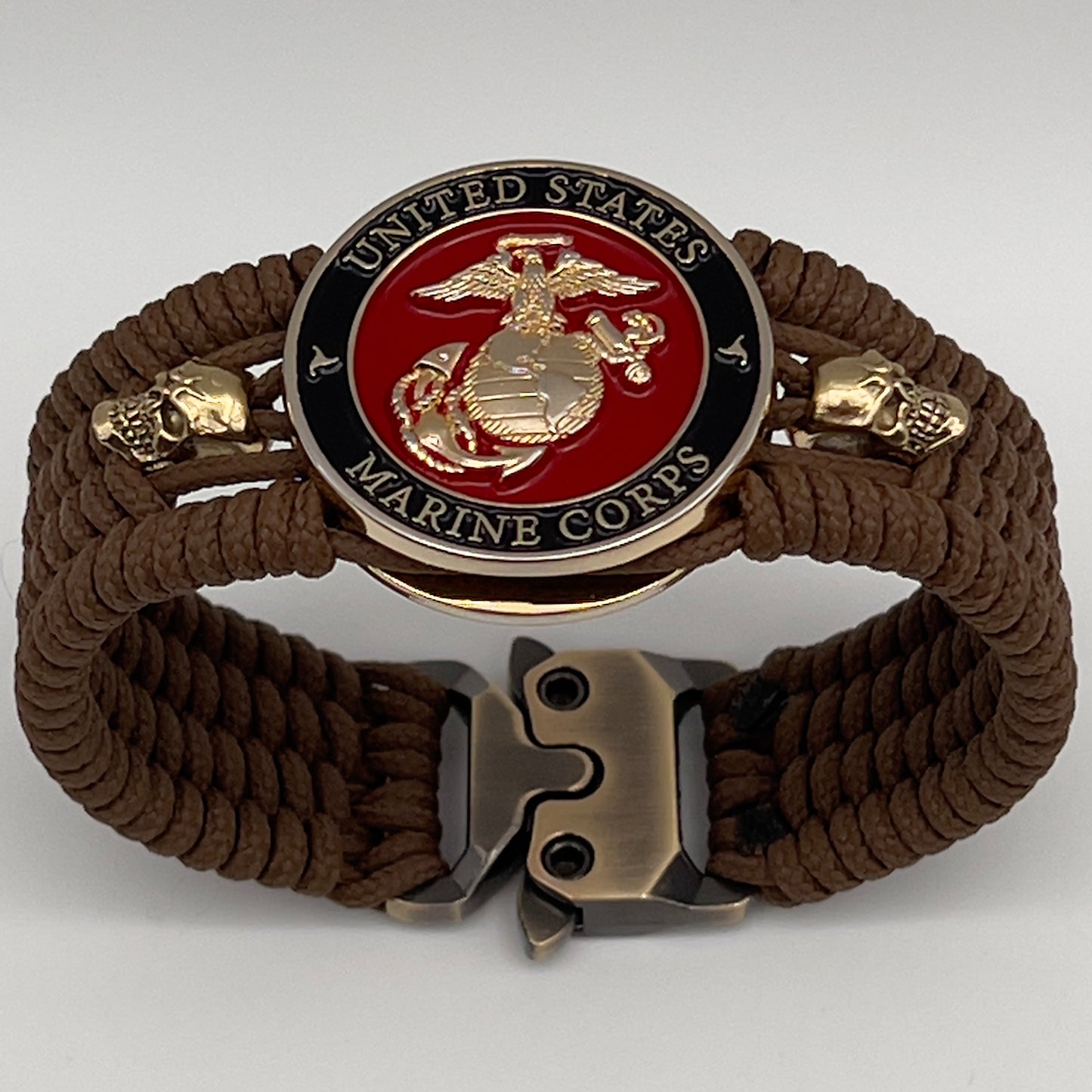 Thin, medium width, flexible and comfortable braided United States Marine Corps bracelet featuring a 24K gold plated USMC officer Eagle Globe and Anchor medallion, two gold plated skulls, a gold Cobra style tactical buckle and woven with Coyote Brown Type-1 paracord.