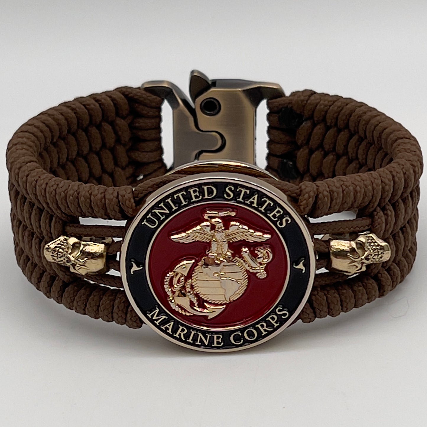 Thin, medium width, flexible and comfortable braided United States Marine Corps bracelet featuring a 24K gold plated USMC officer Eagle Globe and Anchor medallion, two gold plated skulls, a gold Cobra style tactical buckle and woven with Coyote Brown Type-1 paracord.