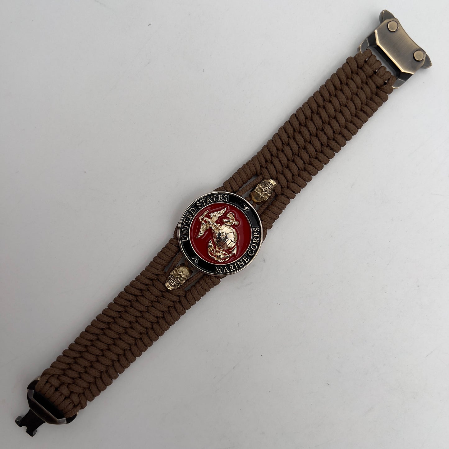 Thin, medium width, flexible and comfortable braided United States Marine Corps bracelet featuring a 24K gold plated USMC officer Eagle Globe and Anchor medallion, two gold plated skulls, a gold Cobra style tactical buckle and woven with Coyote Brown Type-1 paracord.