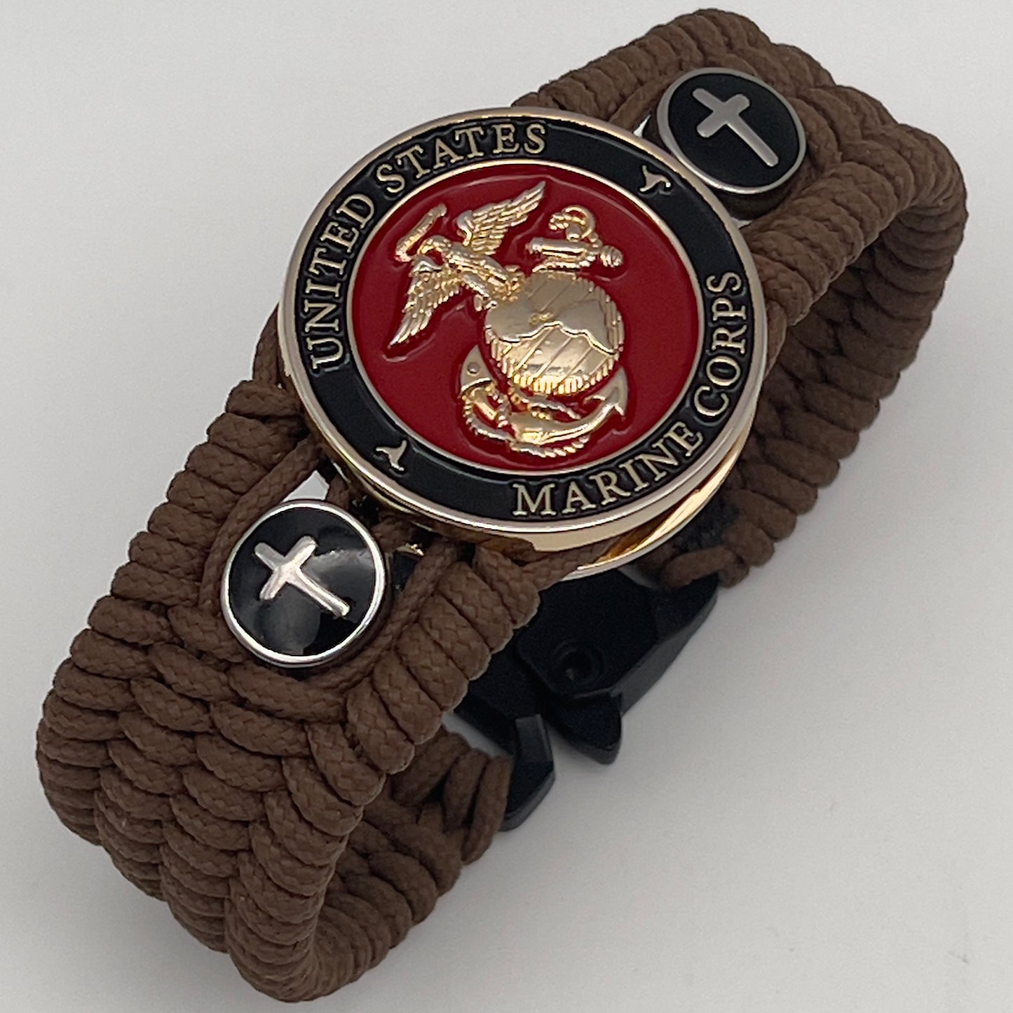 Thin, medium width, flexible and comfortable braided United States Marine Corps bracelet featuring a 24K gold plated USMC officer Eagle Globe and Anchor medallion, two Christian crosses, a black Cobra style tactical buckle and woven with Coyote Brown Type-1 paracord.