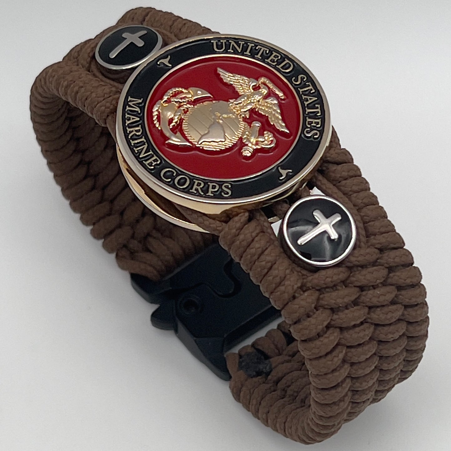 Thin, medium width, flexible and comfortable braided United States Marine Corps bracelet featuring a 24K gold plated USMC officer Eagle Globe and Anchor medallion, two Christian crosses, a black Cobra style tactical buckle and woven with Coyote Brown Type-1 paracord.