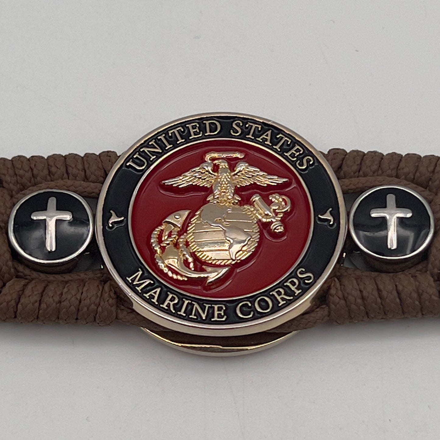 Thin, medium width, flexible and comfortable braided United States Marine Corps bracelet featuring a 24K gold plated USMC officer Eagle Globe and Anchor medallion, two Christian crosses, a black Cobra style tactical buckle and woven with Coyote Brown Type-1 paracord.