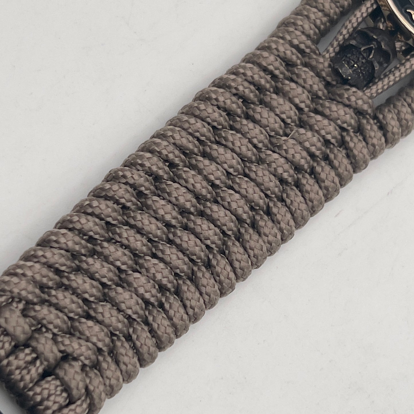 Thin, medium width, flexible and comfortable braided United States Marine Corps bracelet featuring a 24K gold plated USMC officer Eagle Globe and Anchor medallion, two black skulls, a black Cobra style tactical buckle and woven with tan Type-1 paracord.
