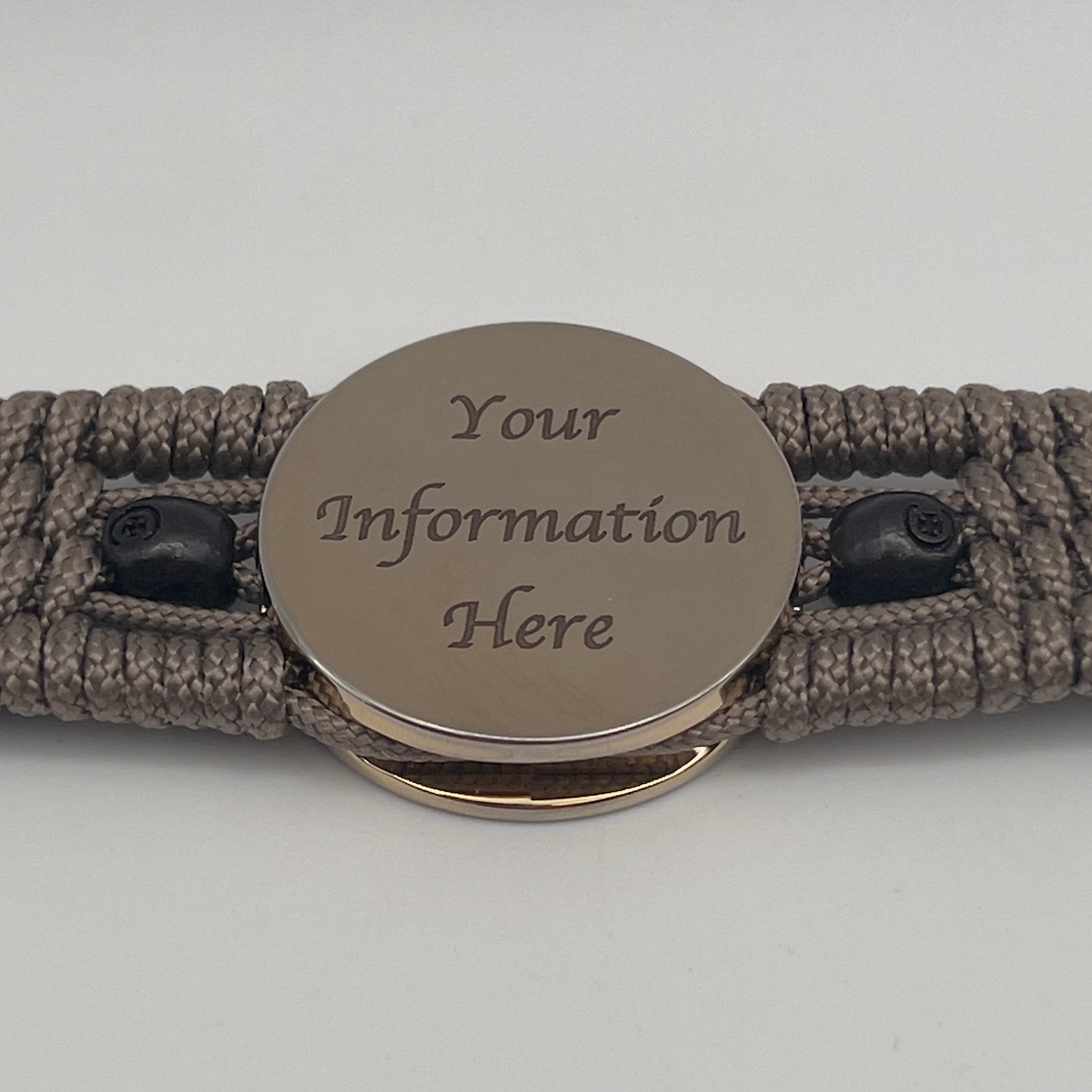Thin, medium width, flexible and comfortable braided United States Marine Corps bracelet featuring a 24K gold plated USMC officer Eagle Globe and Anchor medallion, two black skulls, a black Cobra style tactical buckle and woven with tan Type-1 paracord.