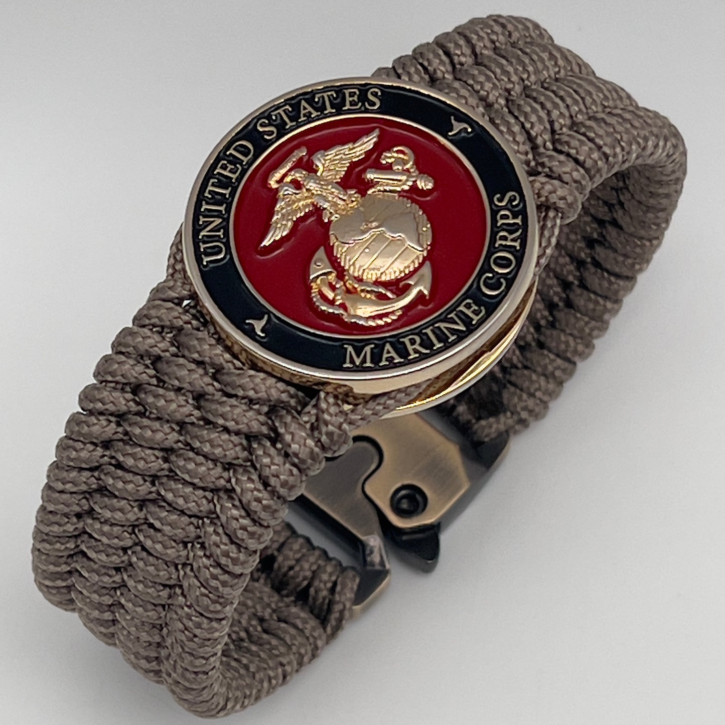 Thin, medium width, flexible and comfortable braided United States Marine Corps bracelet featuring a 24K gold plated USMC officer Eagle Globe and Anchor medallion, a gold Cobra style tactical buckle and woven with Tan Type-1 paracord.