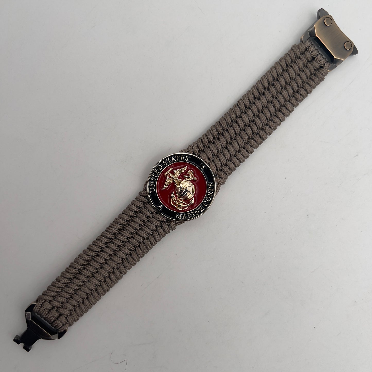 Thin, medium width, flexible and comfortable braided United States Marine Corps bracelet featuring a 24K gold plated USMC officer Eagle Globe and Anchor medallion, a gold Cobra style tactical buckle and woven with Tan Type-1 paracord.