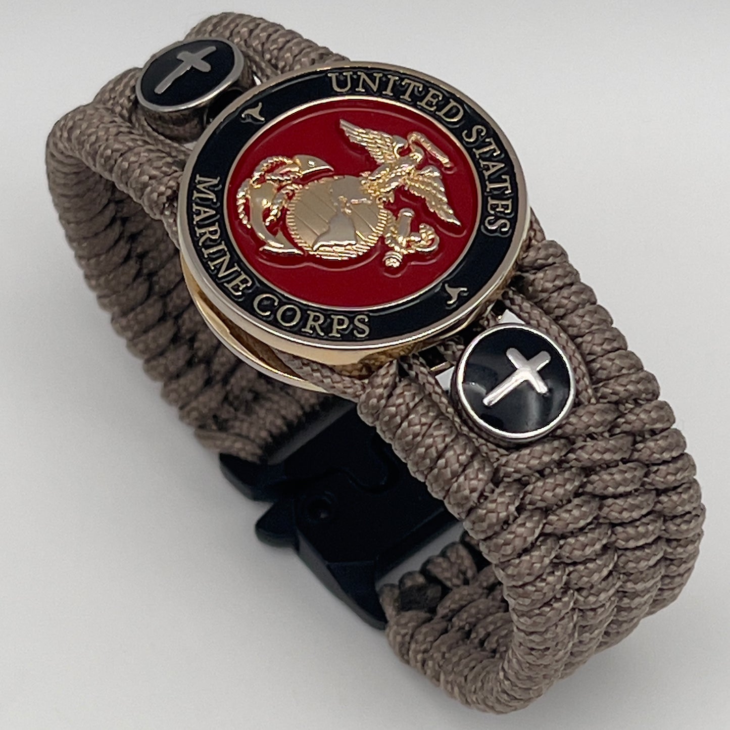 Thin, medium width, flexible and comfortable braided United States Marine Corps bracelet featuring a 24K gold plated USMC officer Eagle Globe and Anchor medallion, two Christian crosses, a black Cobra style tactical buckle and woven with Tan Type-1 paracord.