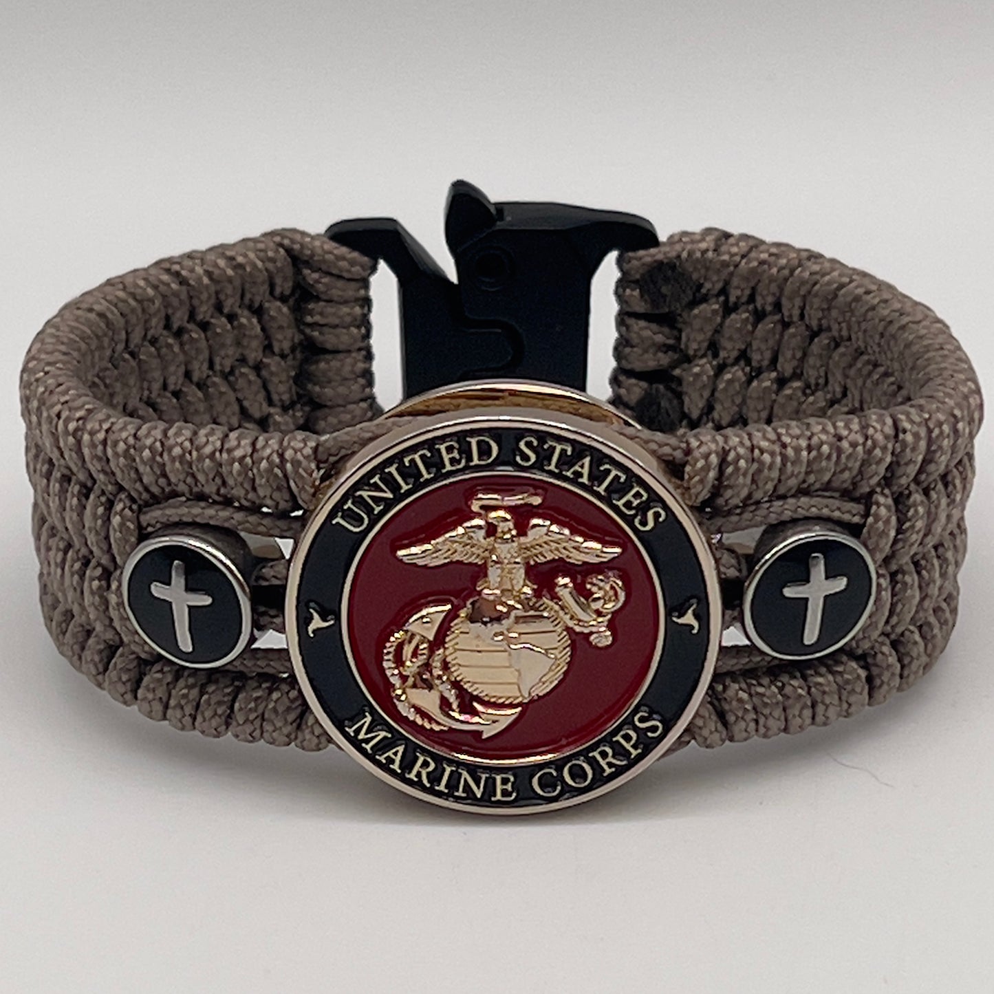 Thin, medium width, flexible and comfortable braided United States Marine Corps bracelet featuring a 24K gold plated USMC officer Eagle Globe and Anchor medallion, two Christian crosses, a black Cobra style tactical buckle and woven with Tan Type-1 paracord.