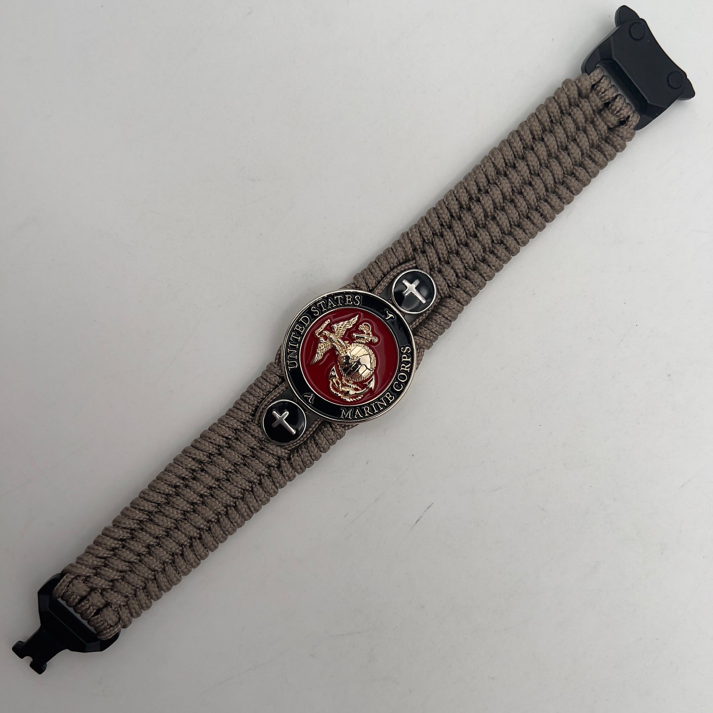 Thin, medium width, flexible and comfortable braided United States Marine Corps bracelet featuring a 24K gold plated USMC officer Eagle Globe and Anchor medallion, two Christian crosses, a black Cobra style tactical buckle and woven with Tan Type-1 paracord.