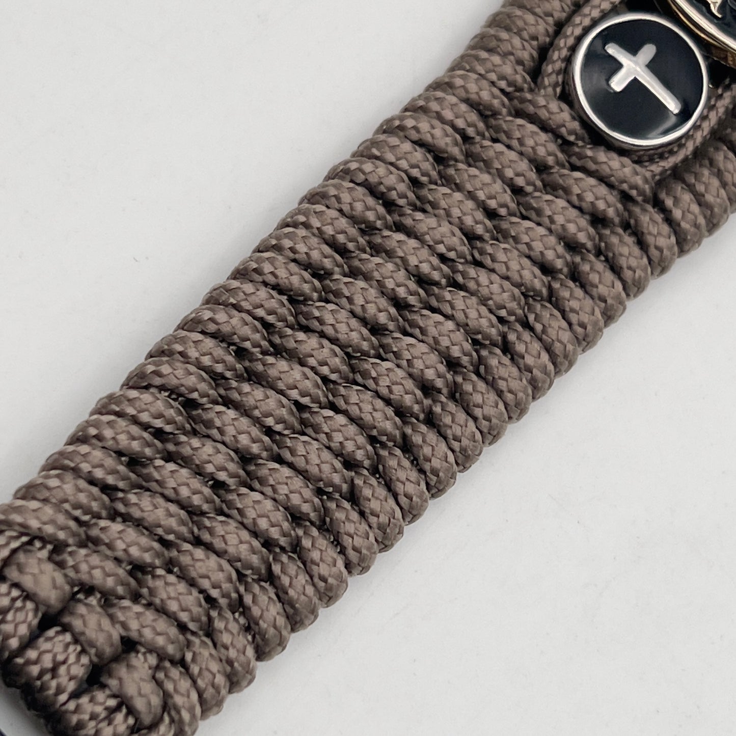 Thin, medium width, flexible and comfortable braided United States Marine Corps bracelet featuring a 24K gold plated USMC officer Eagle Globe and Anchor medallion, two Christian crosses, a black Cobra style tactical buckle and woven with Tan Type-1 paracord.