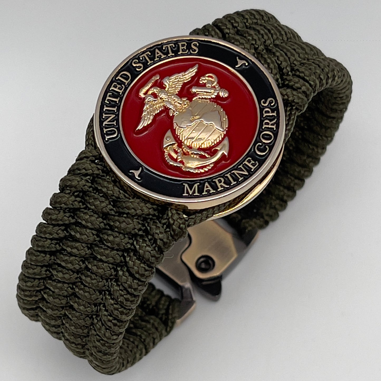 Thin, medium width, flexible and comfortable braided United States Marine Corps bracelet featuring a 24K gold plated USMC officer Eagle Globe and Anchor medallion, a gold Cobra style tactical buckle and woven with Olive Drab Type-1 paracord.