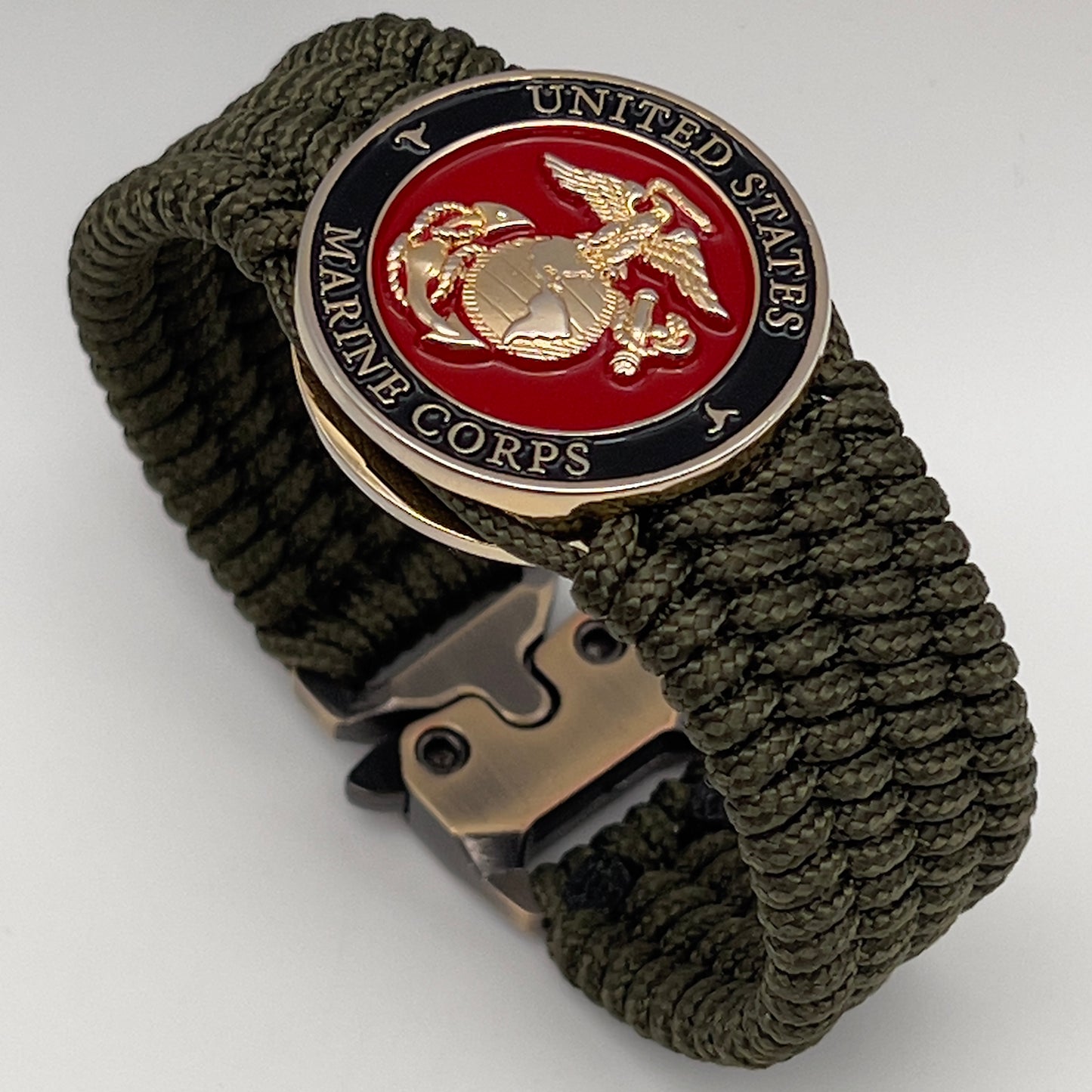 Thin, medium width, flexible and comfortable braided United States Marine Corps bracelet featuring a 24K gold plated USMC officer Eagle Globe and Anchor medallion, a gold Cobra style tactical buckle and woven with Olive Drab Type-1 paracord.