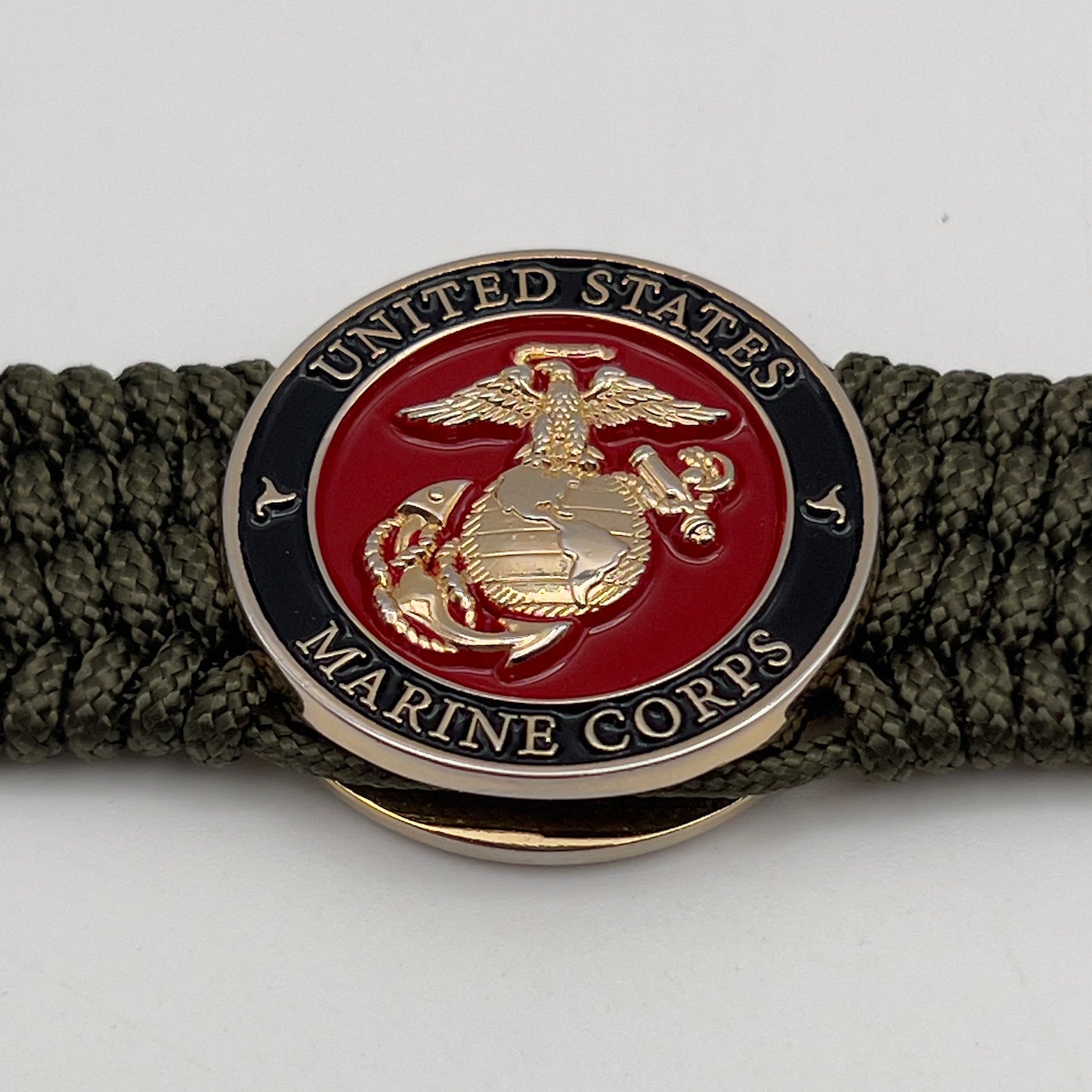 Thin, medium width, flexible and comfortable braided United States Marine Corps bracelet featuring a 24K gold plated USMC officer Eagle Globe and Anchor medallion, a gold Cobra style tactical buckle and woven with Olive Drab Type-1 paracord.