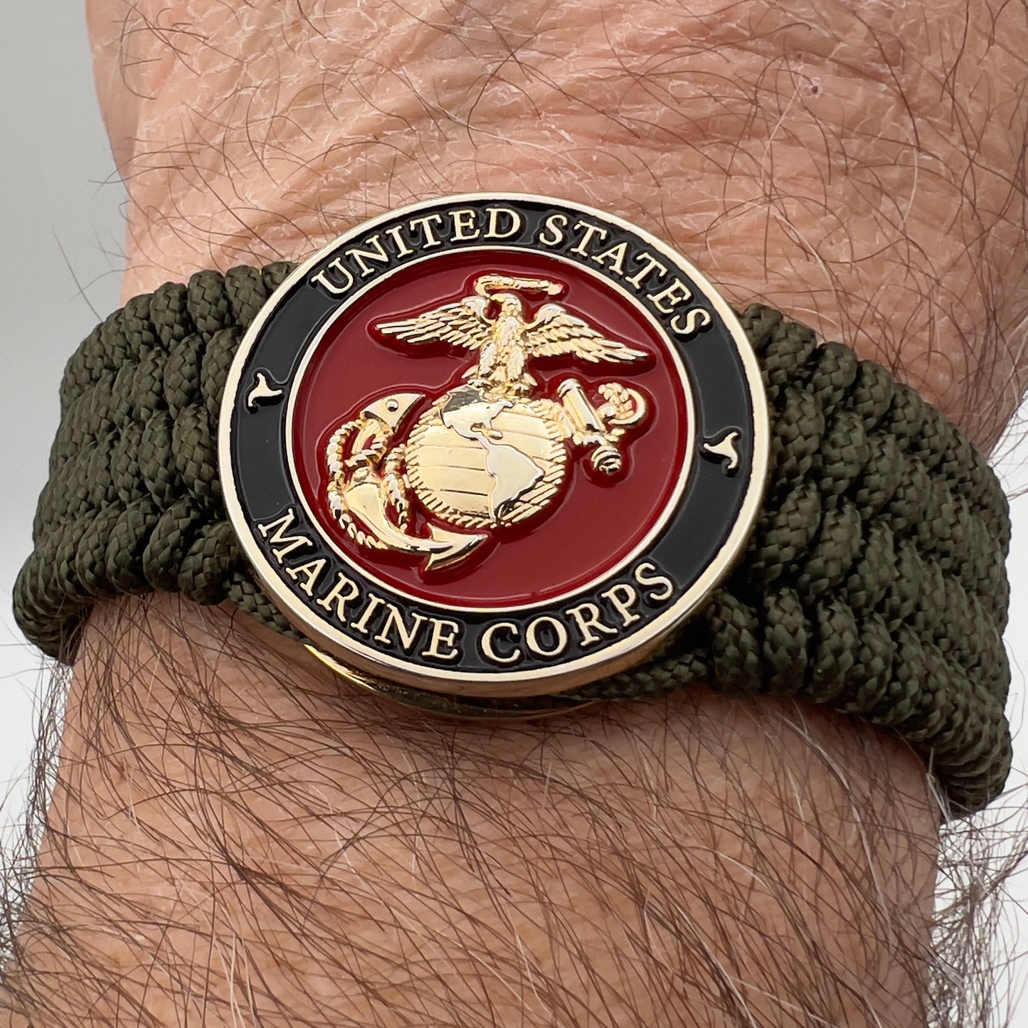 Thin, medium width, flexible and comfortable braided United States Marine Corps bracelet featuring a 24K gold plated USMC officer Eagle Globe and Anchor medallion, a gold Cobra style tactical buckle and woven with Olive Drab Type-1 paracord.