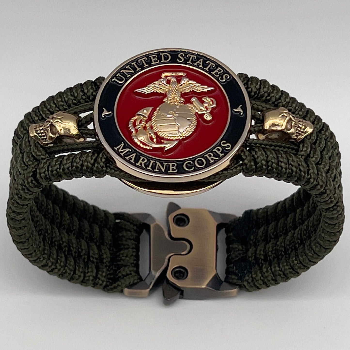 Thin, medium width, flexible and comfortable braided United States Marine Corps bracelet featuring a 24K gold plated USMC officer Eagle Globe and Anchor medallion, two gold plated skulls, a gold Cobra style tactical buckle and woven with Olive Drab Type-1 paracord.
