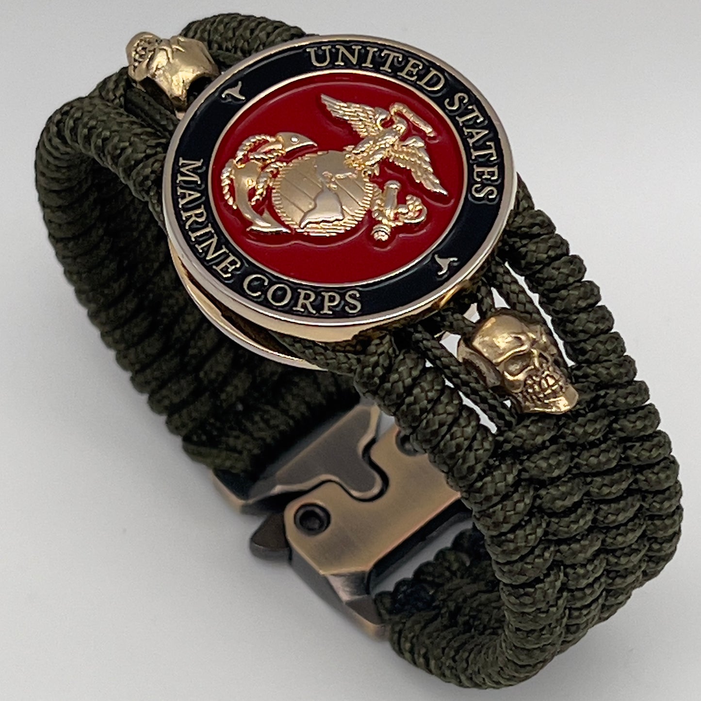 Thin, medium width, flexible and comfortable braided United States Marine Corps bracelet featuring a 24K gold plated USMC officer Eagle Globe and Anchor medallion, two gold plated skulls, a gold Cobra style tactical buckle and woven with Olive Drab Type-1 paracord.