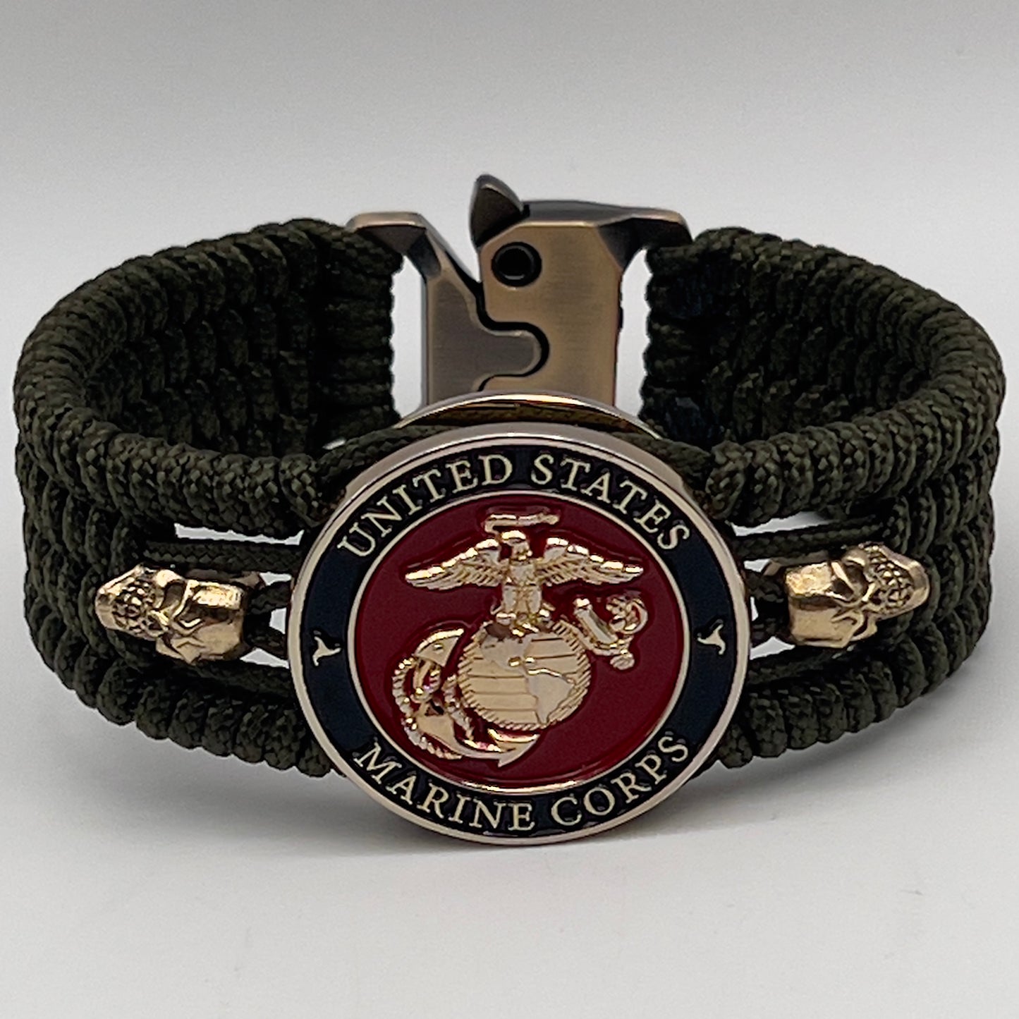 Thin, medium width, flexible and comfortable braided United States Marine Corps bracelet featuring a 24K gold plated USMC officer Eagle Globe and Anchor medallion, two gold plated skulls, a gold Cobra style tactical buckle and woven with Olive Drab Type-1 paracord.