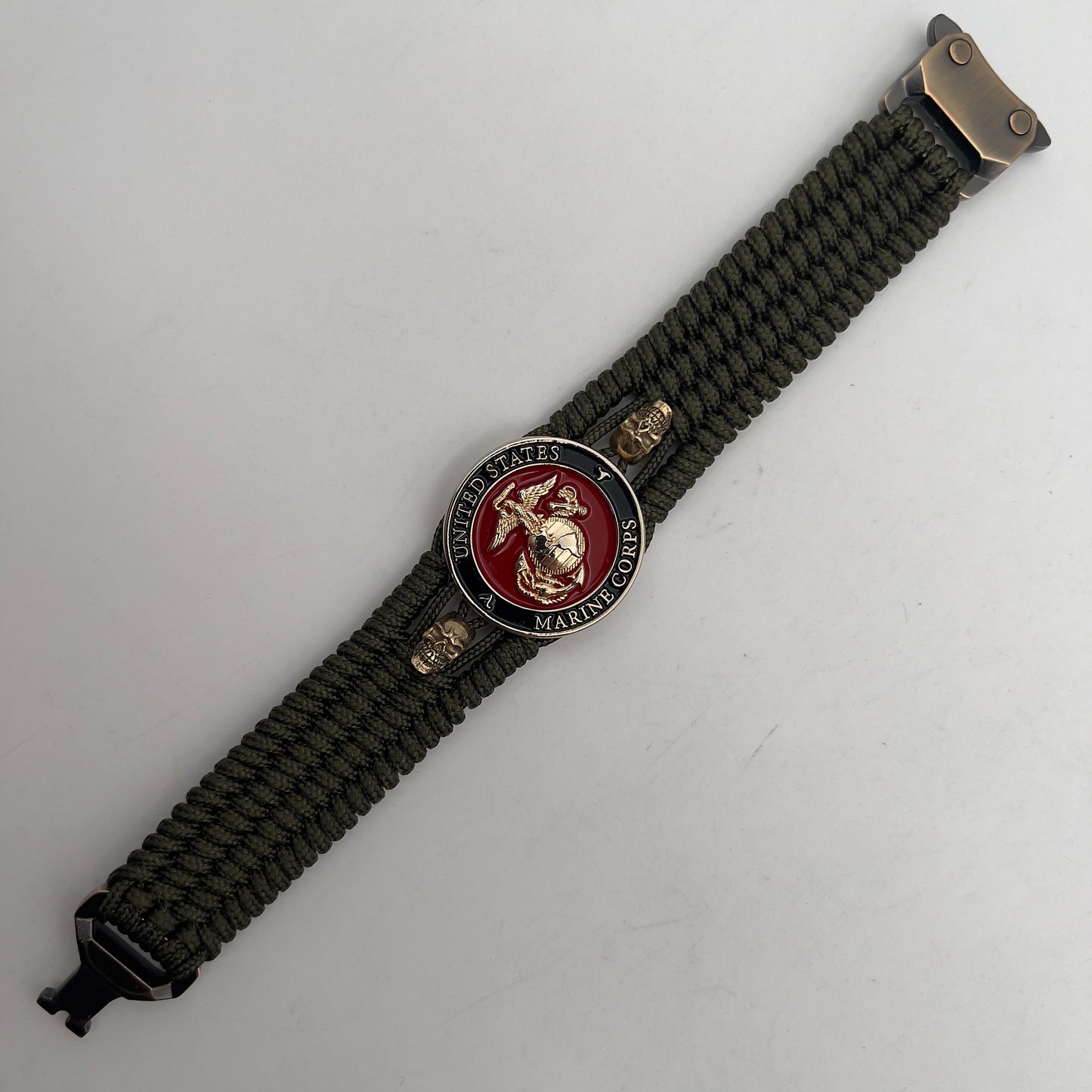Thin, medium width, flexible and comfortable braided United States Marine Corps bracelet featuring a 24K gold plated USMC officer Eagle Globe and Anchor medallion, two gold plated skulls, a gold Cobra style tactical buckle and woven with Olive Drab Type-1 paracord.