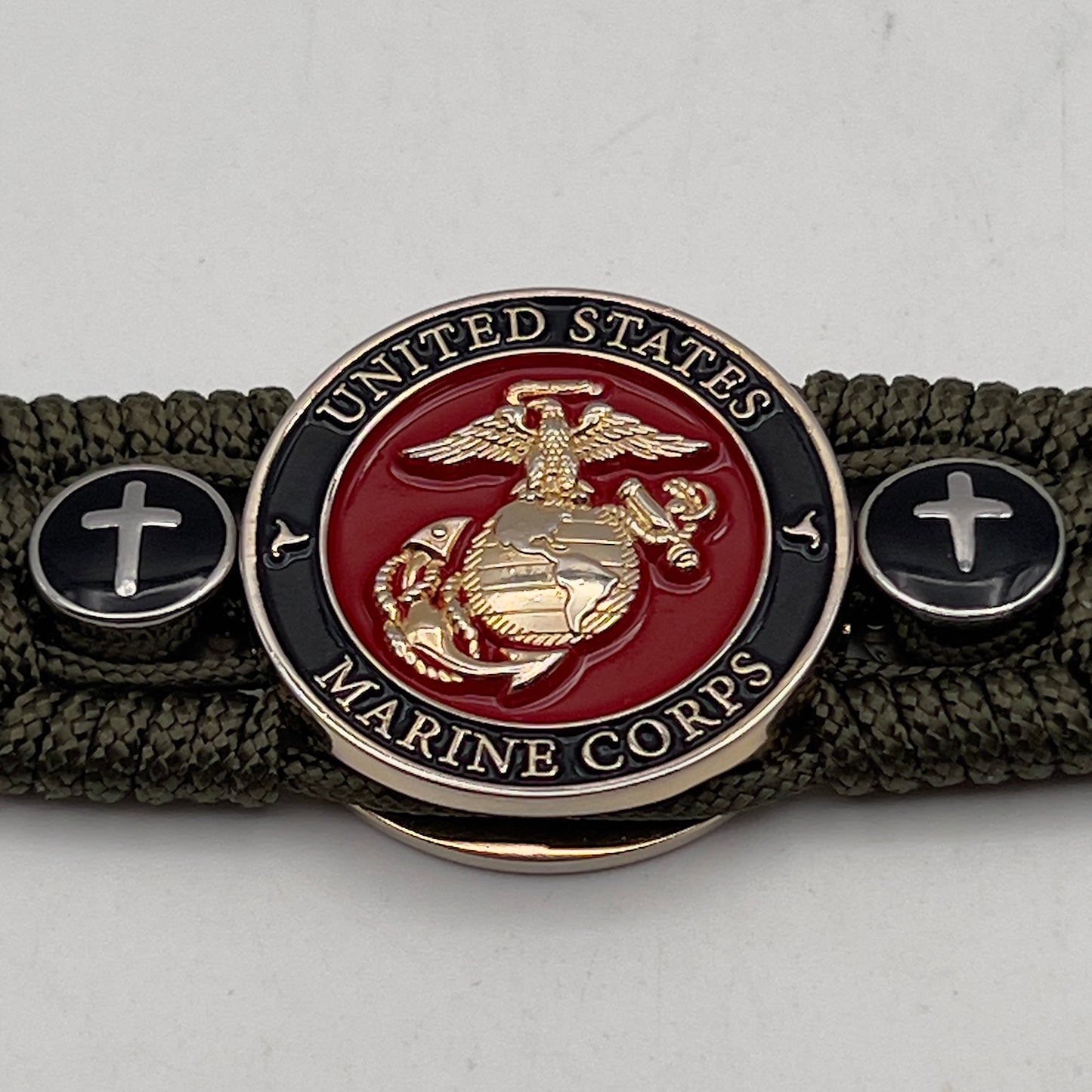 Thin, medium width, flexible and comfortable braided United States Marine Corps bracelet featuring a 24K gold plated USMC officer Eagle Globe and Anchor medallion, two Christian crosses, a black Cobra style tactical buckle and woven with Olive Drab Type-1 paracord.
