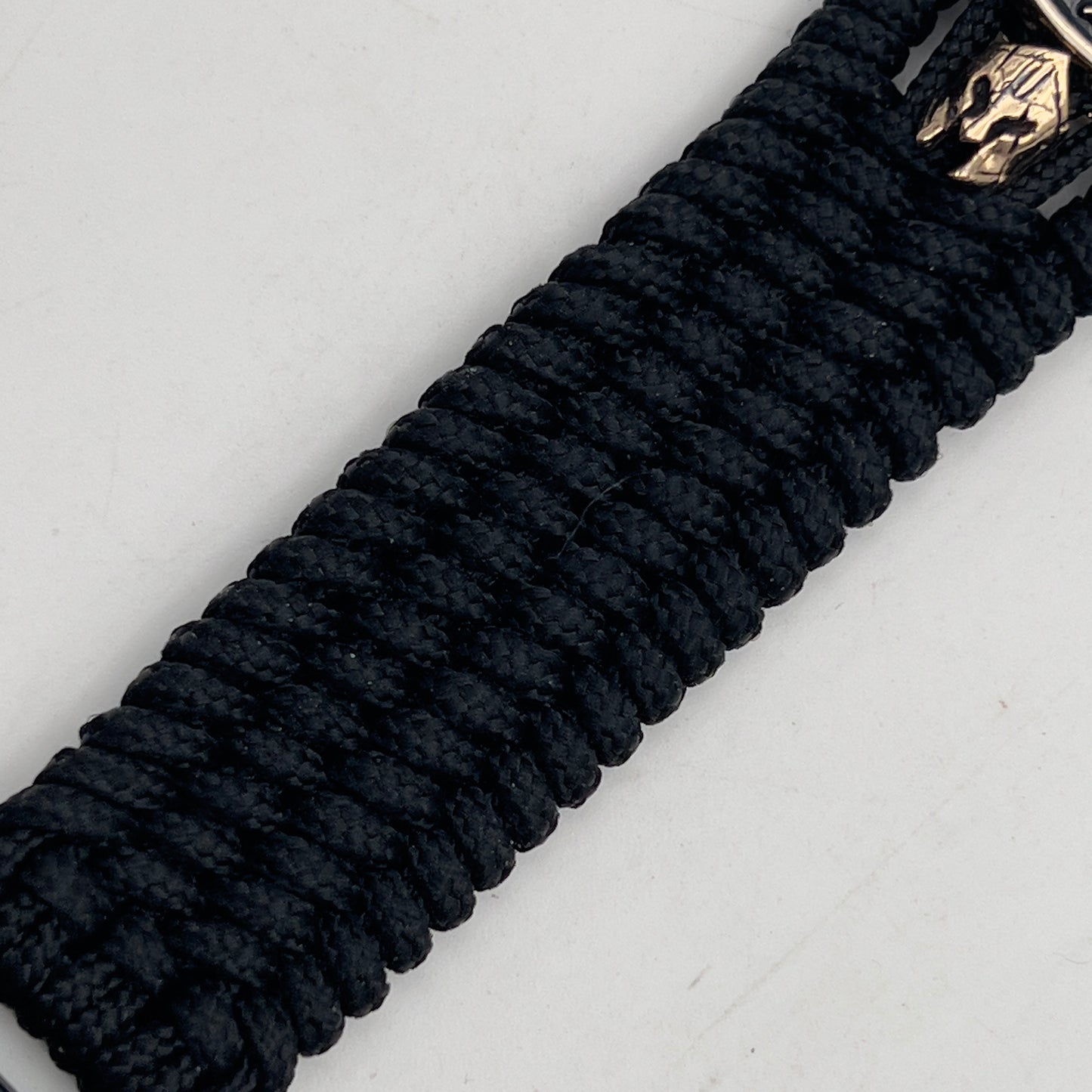 Thin, medium width, flexible and comfortable braided United States Marine Corps bracelet featuring a 24K gold plated USMC officer Eagle Globe and Anchor medallion, two brass Spartan helmets, a black Cobra style tactical buckle and woven with black Type-1 paracord.