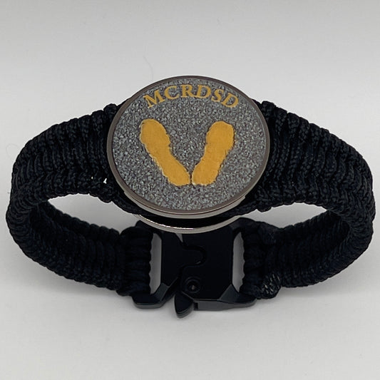 Thin, narrow, flexible and comfortable braided United States Marine Corps Recruit Depot Yellow Footprints bracelet featuring a black nickel plated UV enamel painted medallion replica of an actual set of USMC footprints, a black Cobra style tactical buckle and woven with black Type-1 paracord.