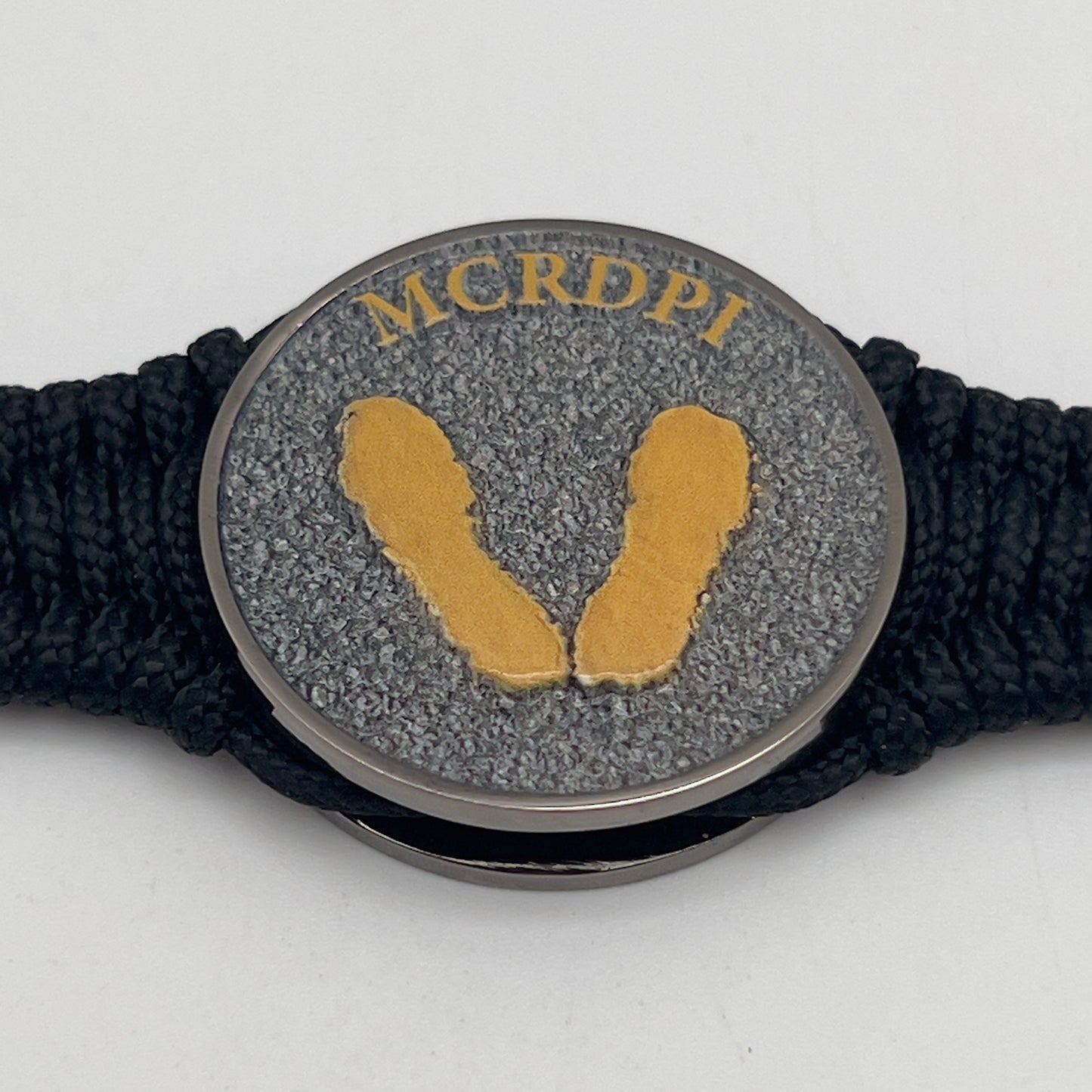 Thin, narrow, flexible and comfortable braided United States Marine Corps Recruit Depot Yellow Footprints bracelet featuring a black nickel plated UV enamel painted medallion replica of an actual set of USMC footprints, a black Cobra style tactical buckle and woven with black Type-1 paracord.