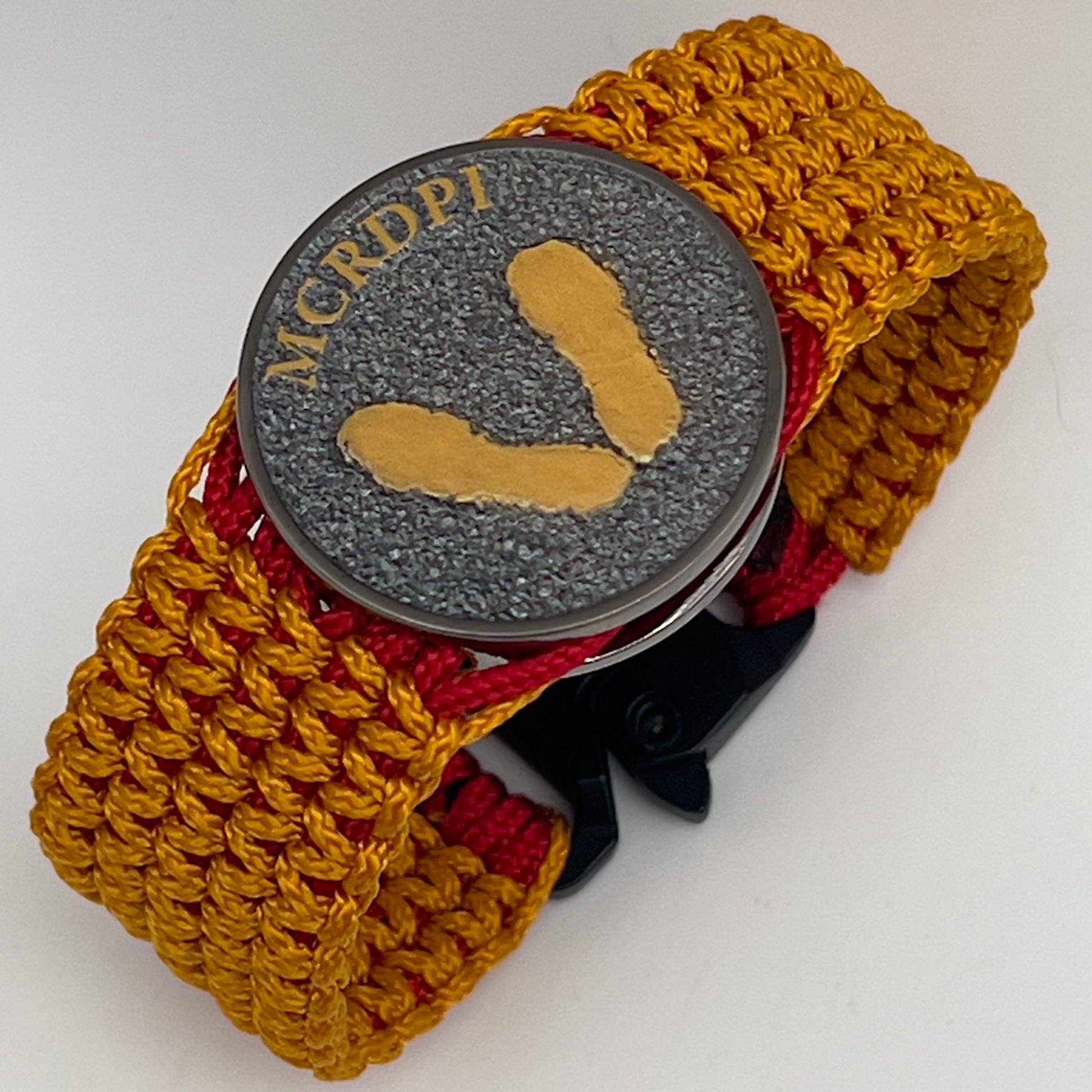 Thin, narrow, flexible and comfortable braided United States Marine Corps Recruit Depot Yellow Footprints bracelet featuring a black nickel plated UV enamel painted medallion replica of an actual set of USMC footprints, a black Cobra style tactical buckle and woven with Imperial Red type-1 paracord and Goldenrod micro cord.