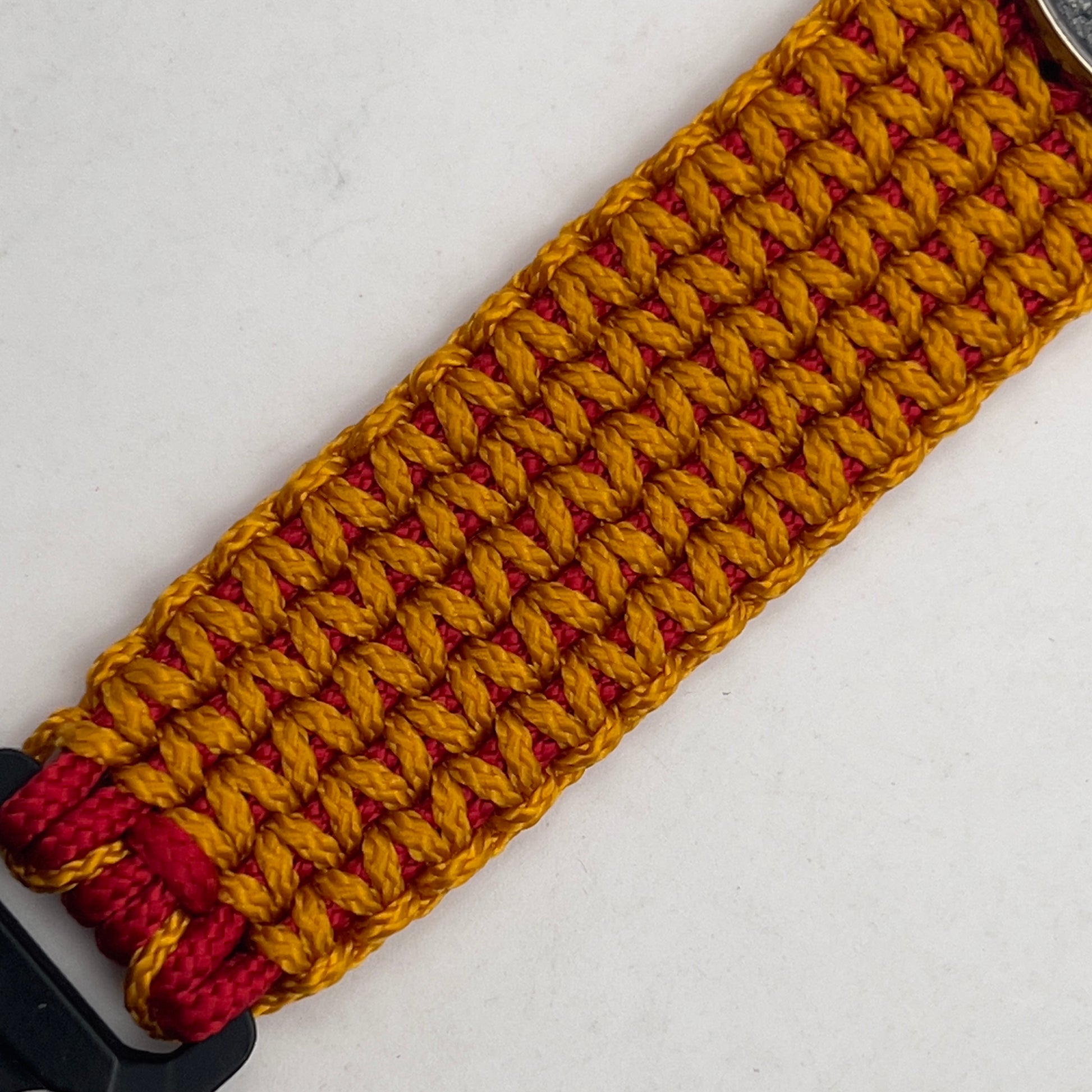 Thin, narrow, flexible and comfortable braided United States Marine Corps Recruit Depot Yellow Footprints bracelet featuring a black nickel plated UV enamel painted medallion replica of an actual set of USMC footprints, a black Cobra style tactical buckle and woven with Imperial Red type-1 paracord and Goldenrod micro cord.