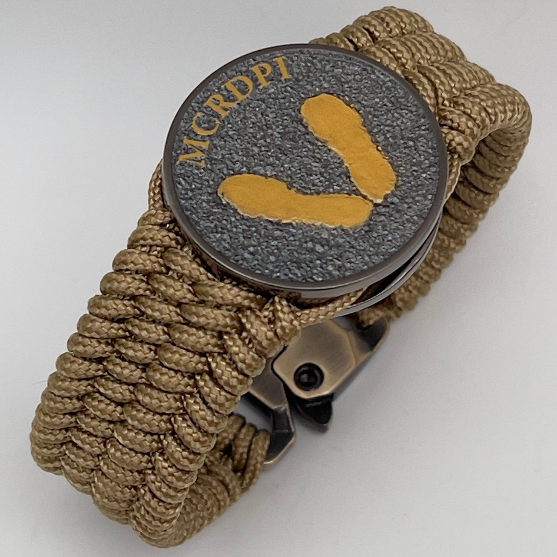Thin, wide, flexible and comfortable braided United States Marine Corps Recruit Depot Yellow Footprints bracelet featuring a black nickel plated UV enamel painted medallion replica of an actual set of USMC footprints, a gold Cobra style tactical buckle and woven with gold Type-1 paracord.