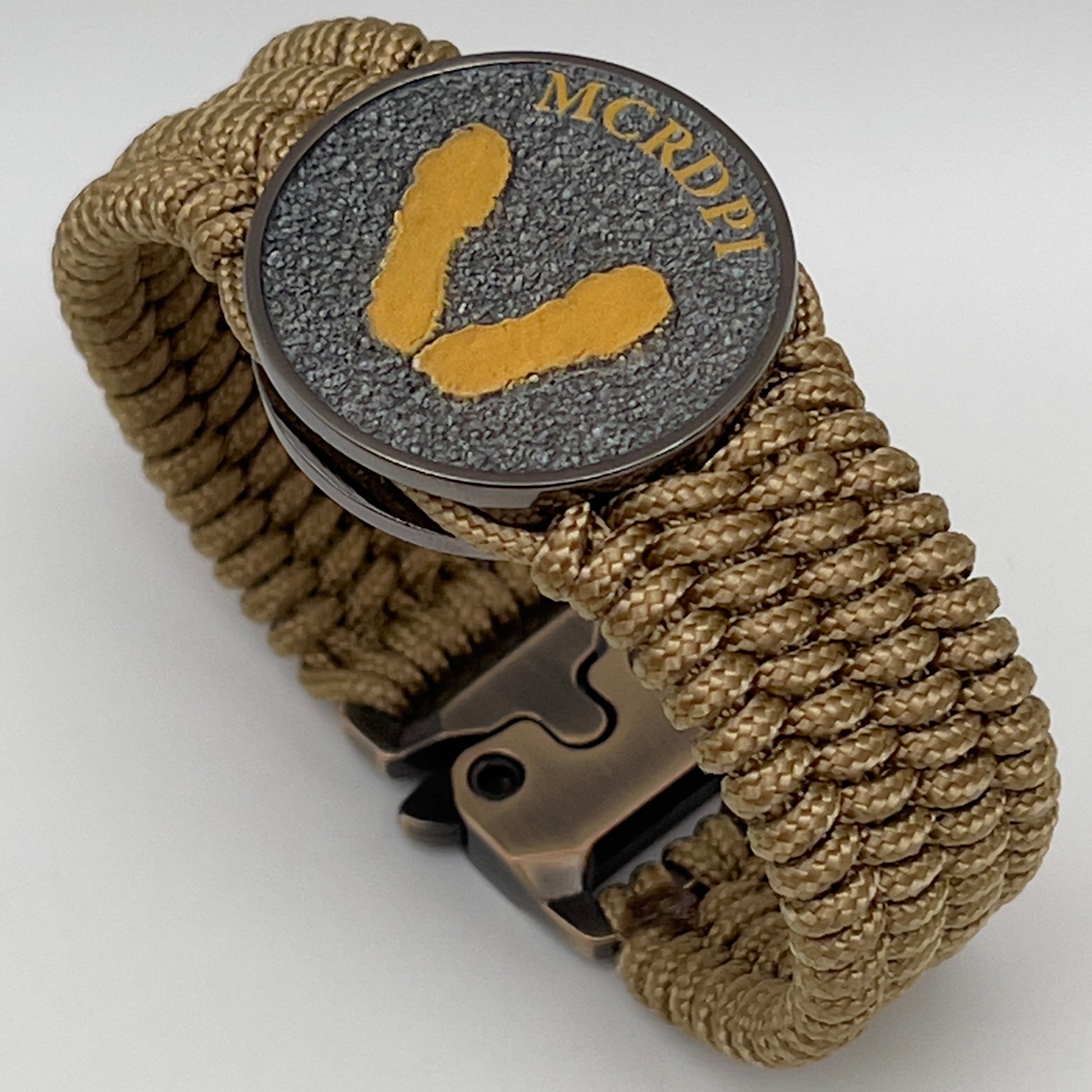 Thin, wide, flexible and comfortable braided United States Marine Corps Recruit Depot Yellow Footprints bracelet featuring a black nickel plated UV enamel painted medallion replica of an actual set of USMC footprints, a gold Cobra style tactical buckle and woven with gold Type-1 paracord.