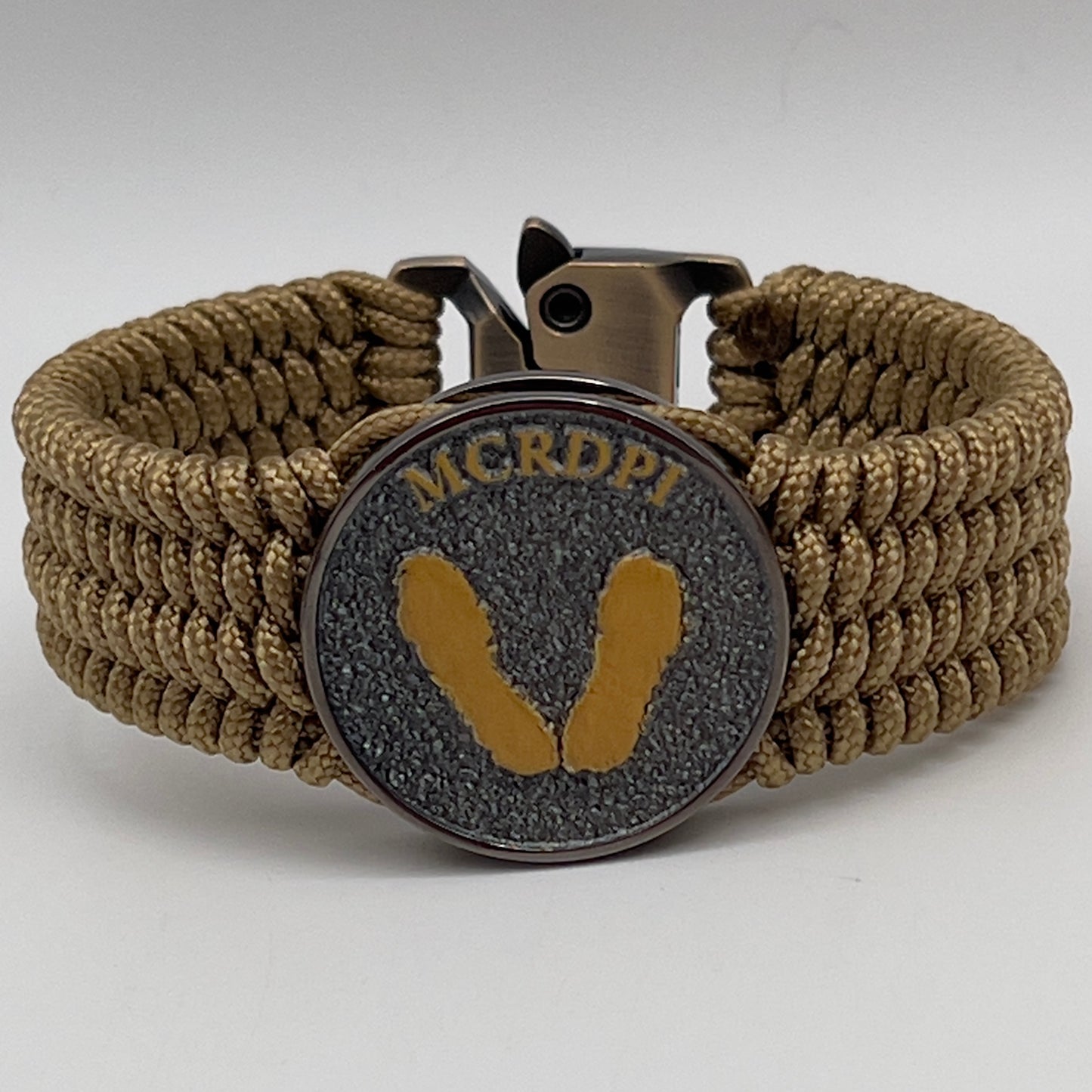 Thin, wide, flexible and comfortable braided United States Marine Corps Recruit Depot Yellow Footprints bracelet featuring a black nickel plated UV enamel painted medallion replica of an actual set of USMC footprints, a gold Cobra style tactical buckle and woven with gold Type-1 paracord.