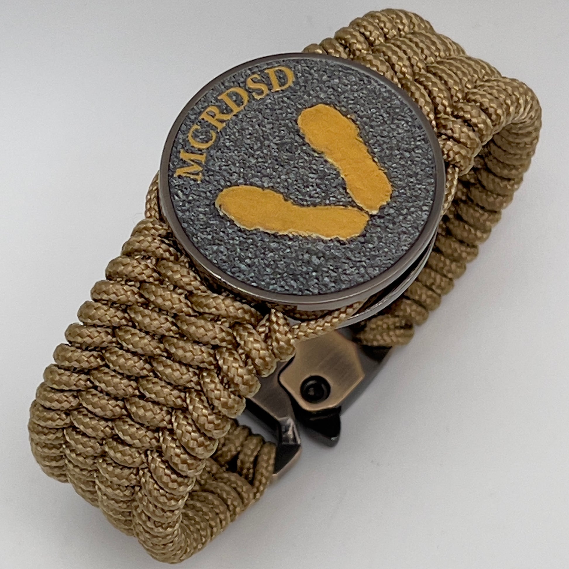 Thin, wide, flexible and comfortable braided United States Marine Corps Recruit Depot Yellow Footprints bracelet featuring a black nickel plated UV enamel painted medallion replica of an actual set of USMC footprints, a gold Cobra style tactical buckle and woven with gold Type-1 paracord.